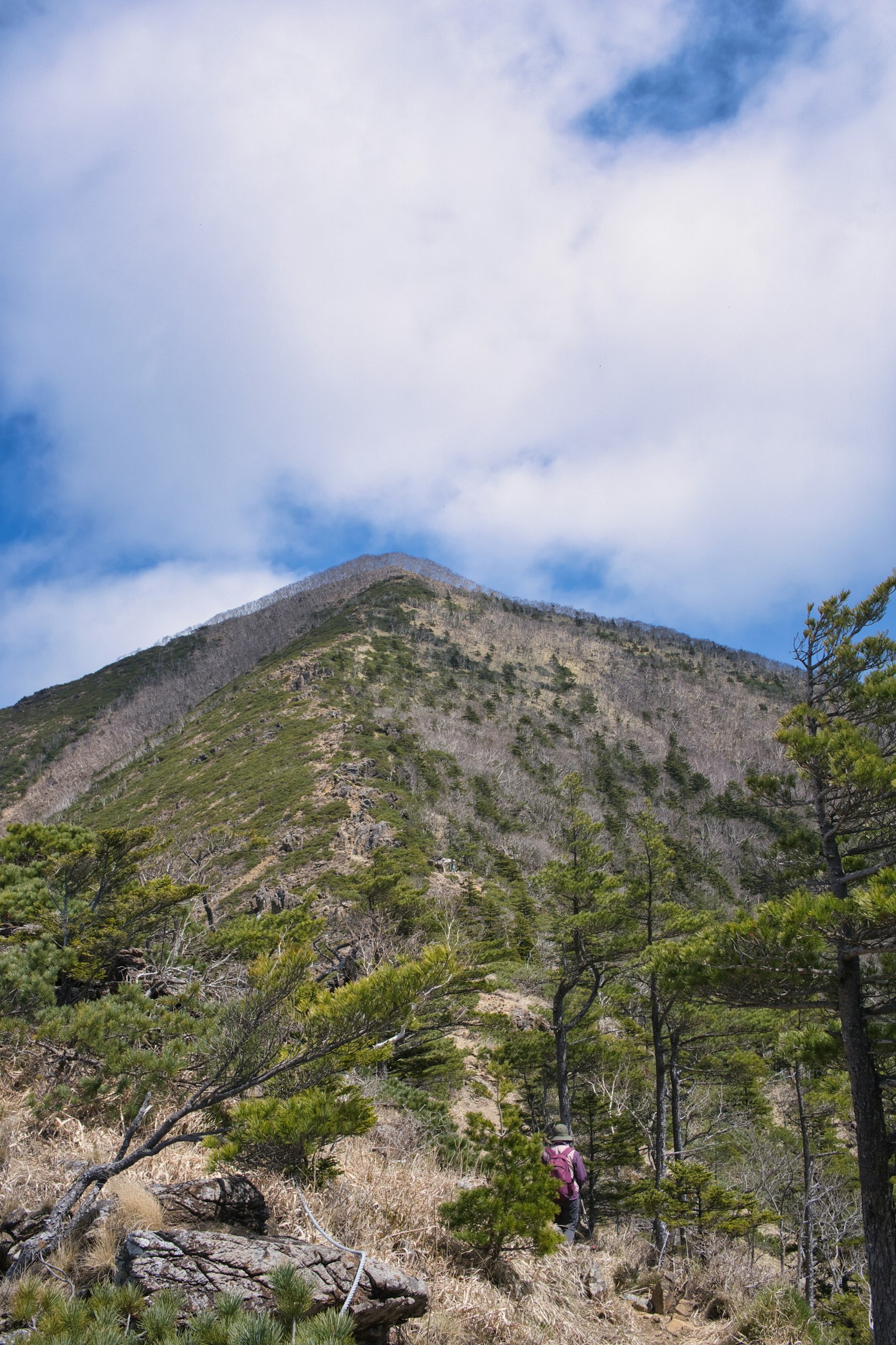 Wanderer auf einem Berghang mit blauem Himmel