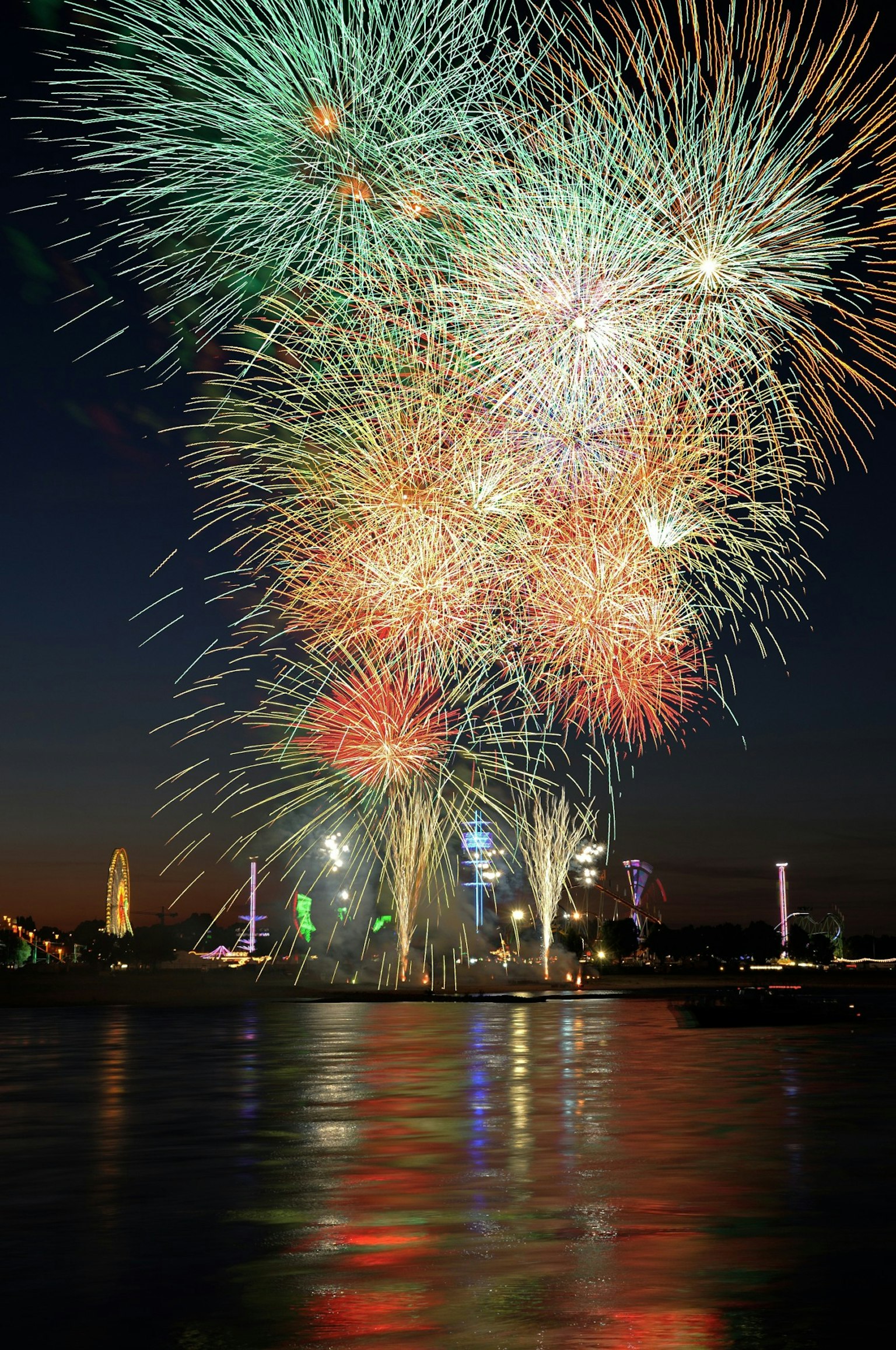 Bunte Feuerwerke, die am Nachthimmel explodieren und sich im Wasser spiegeln