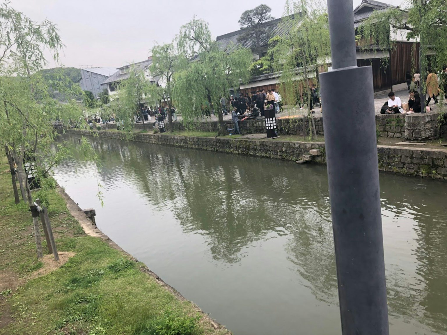 Pemandangan tenang sungai dengan pohon willow dan orang-orang