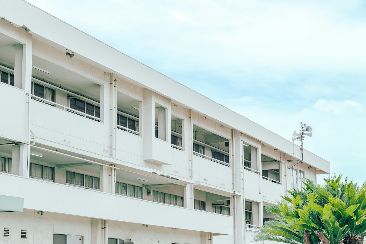 Vista exterior de un edificio escolar blanco bajo un cielo azul