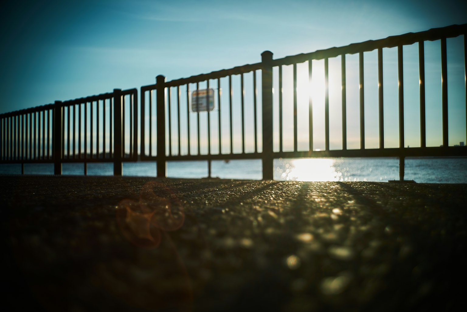 Imagen de una cerca junto al mar con reflejos del atardecer
