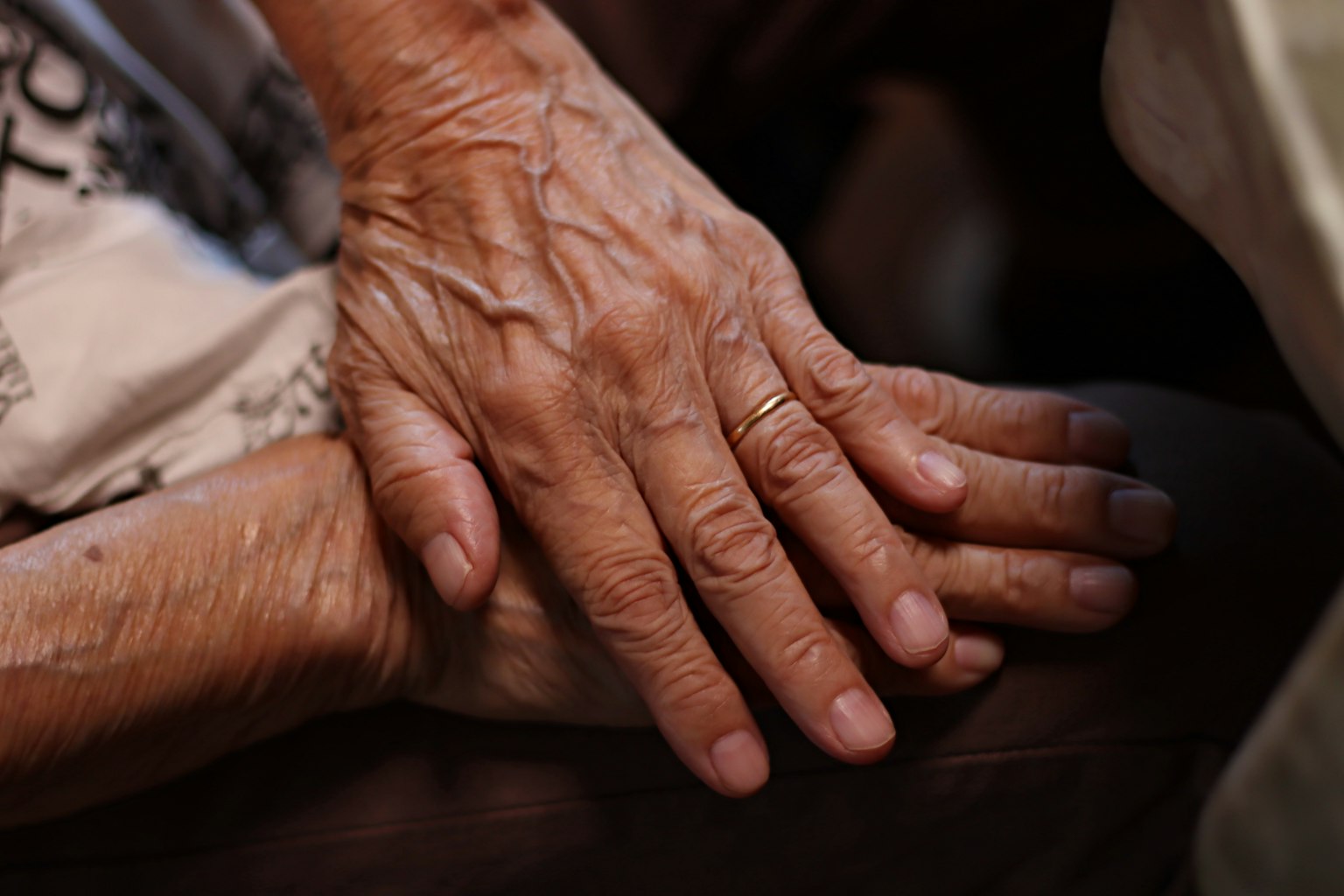 Tangan tua bertumpuk dalam gestur hangat