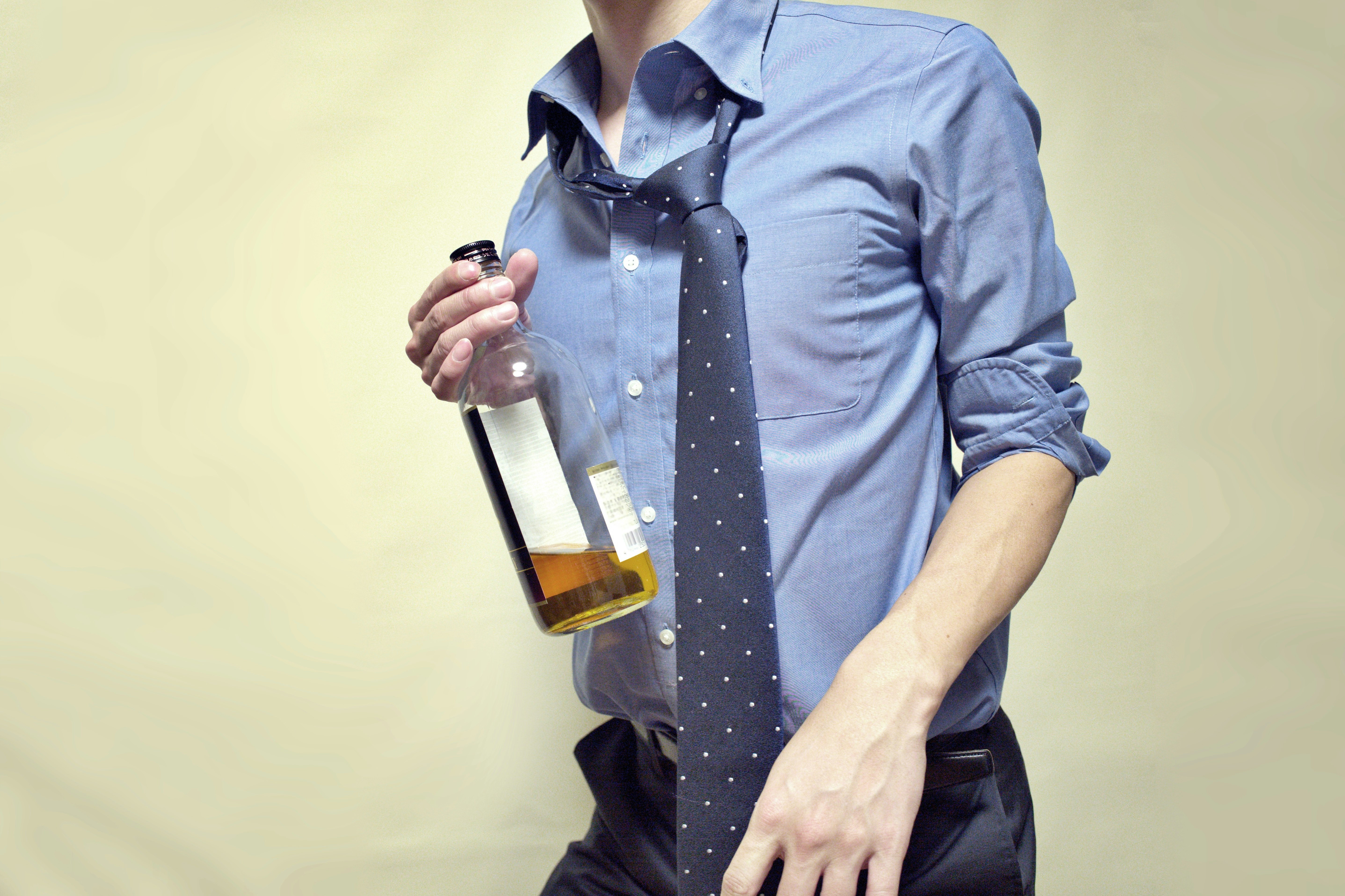 hombre con corbata sosteniendo una botella de cerveza