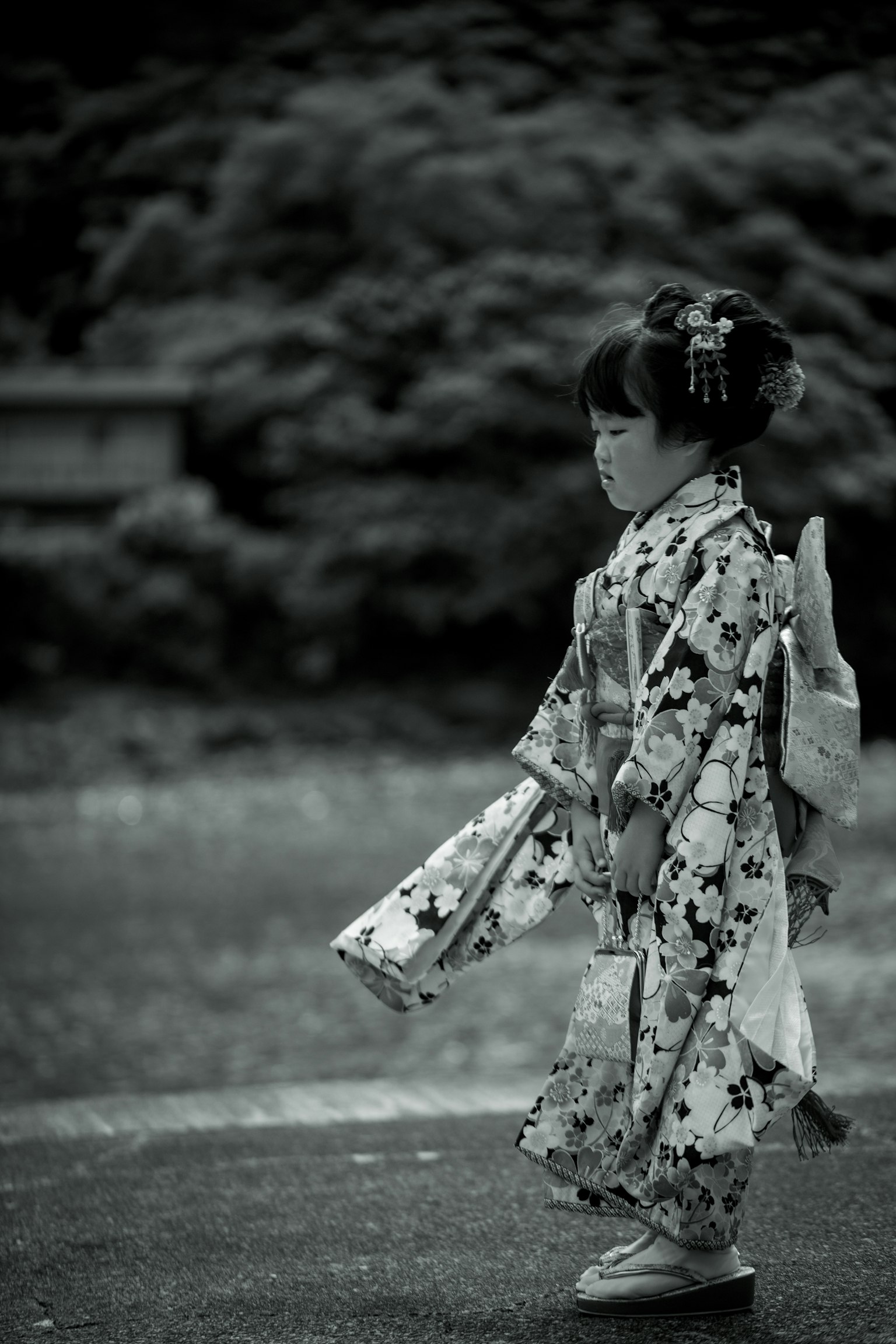 Una niña en kimono caminando en una fotografía en blanco y negro