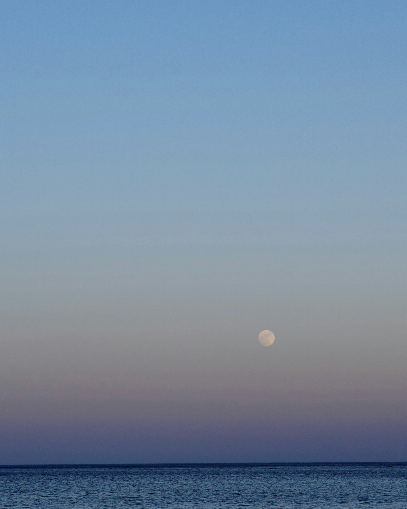 水平線に沈む夕暮れの海と空のグラデーション