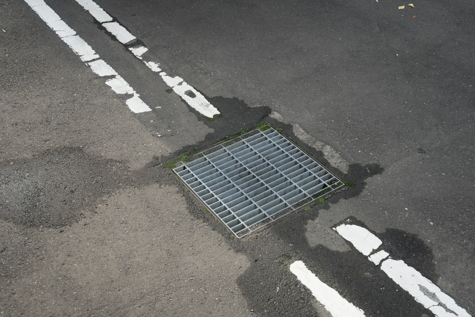 路面上排水格柵的圖像，帶有白色條紋