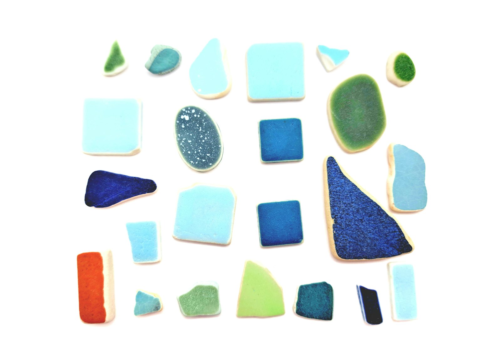 Collection de morceaux de verre de plage colorés disposés sur un fond blanc