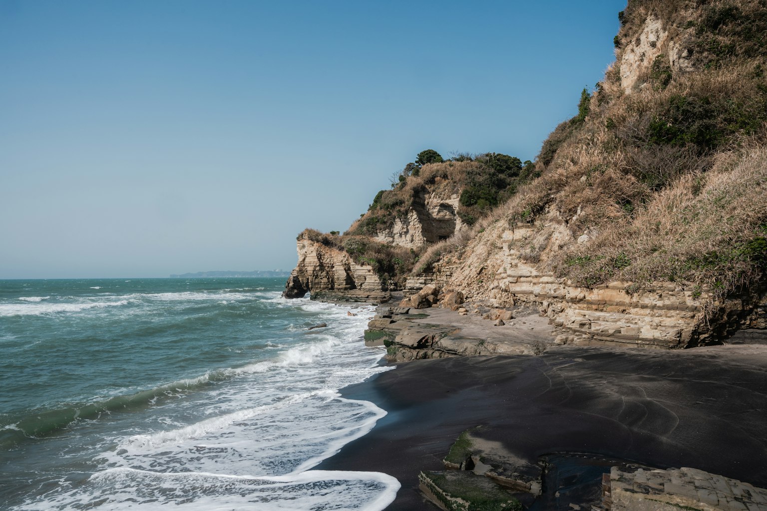 Paisaje costero con acantilados cielo azul y olas rompiendo