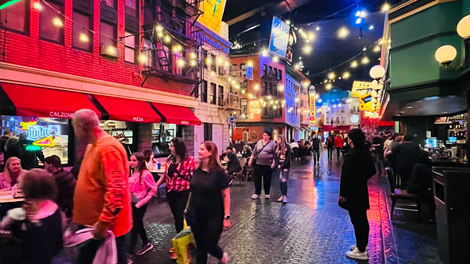Personnes marchant dans une rue colorée avec des lumières vives et une atmosphère animée