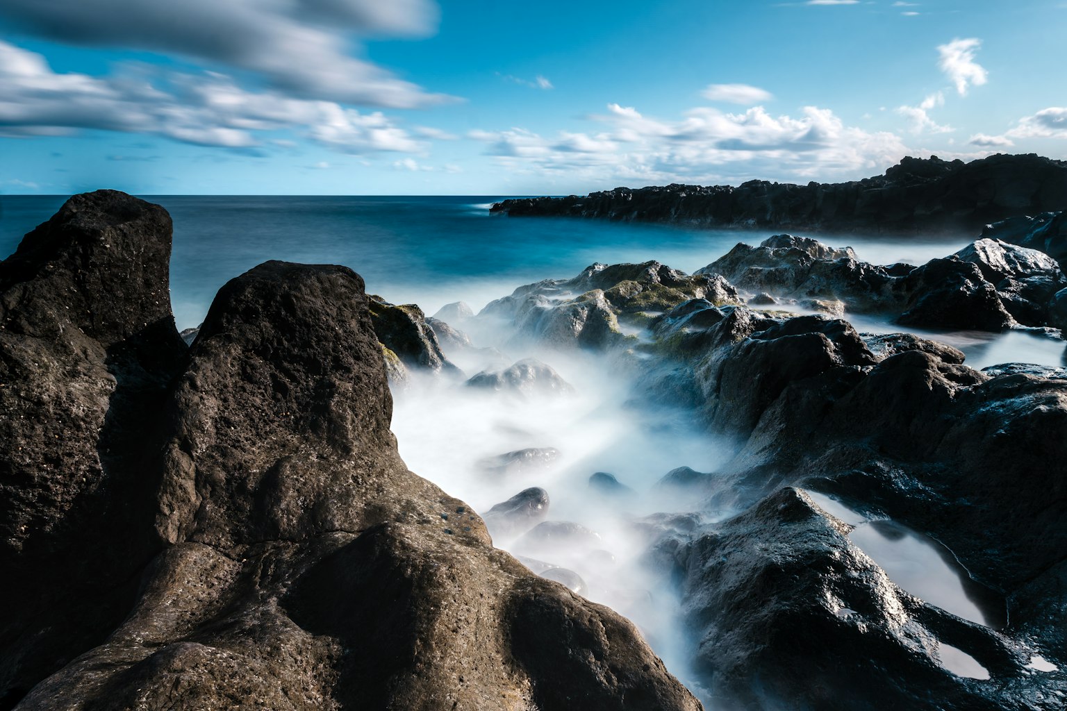 海岸风景，崎岖的岩石和波浪在蓝天下