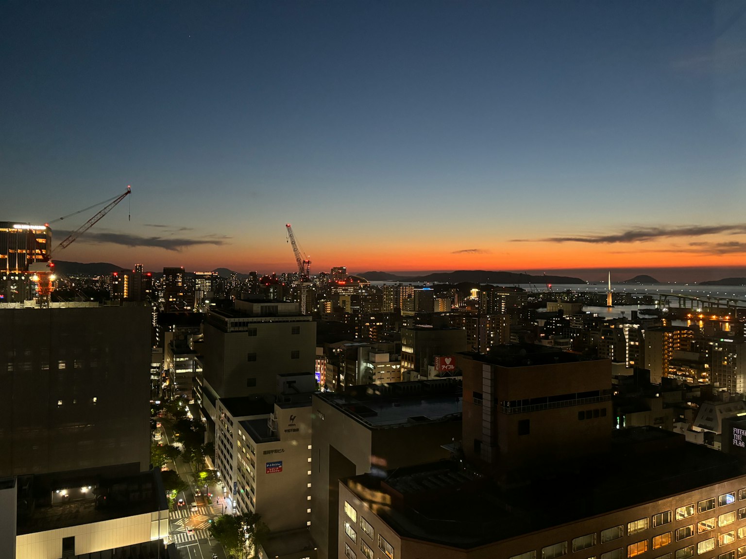 Skyline cittadina al tramonto con grattacieli e gru visibili