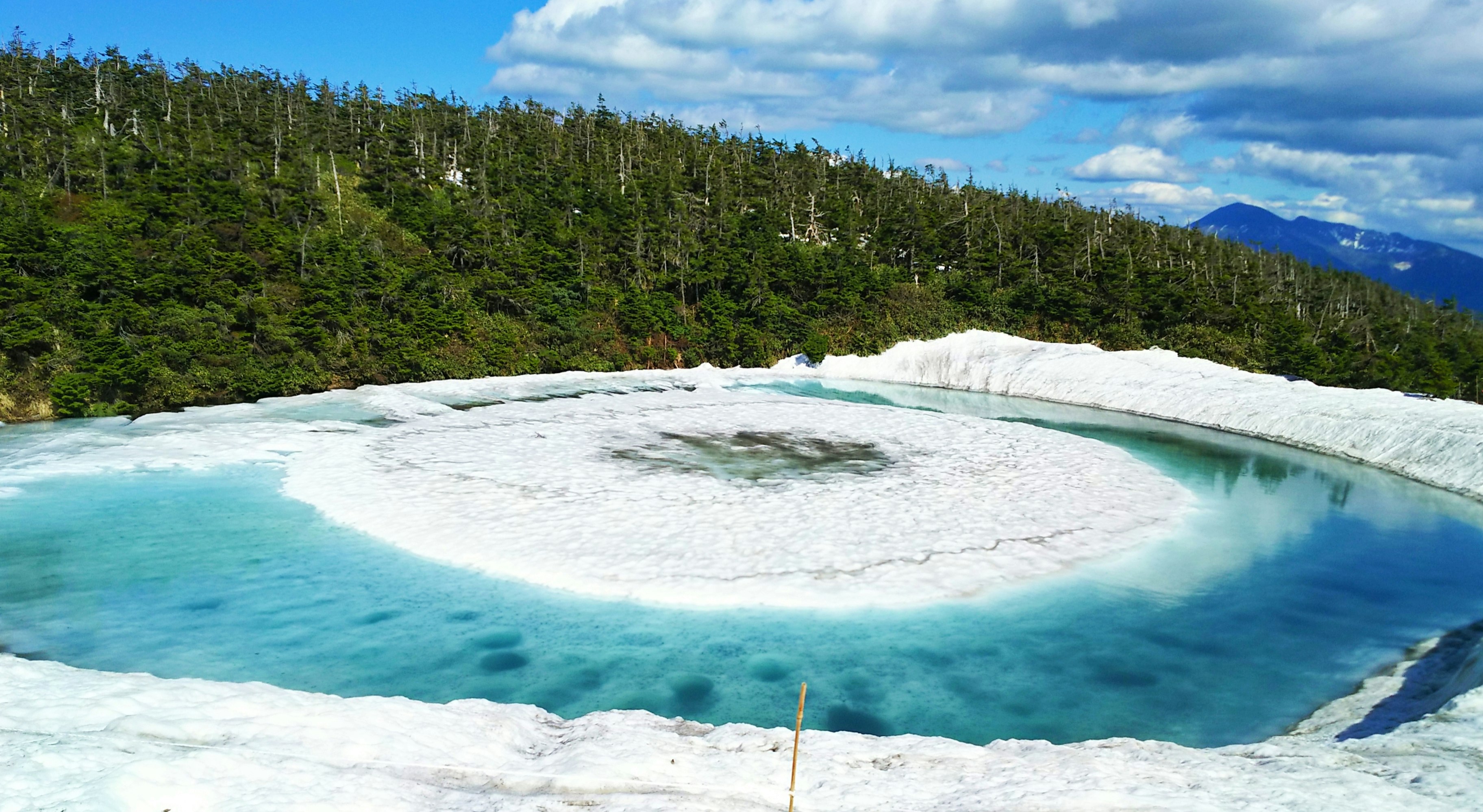 エメラルド色の湯と白い湯だまりのある温泉の滝口