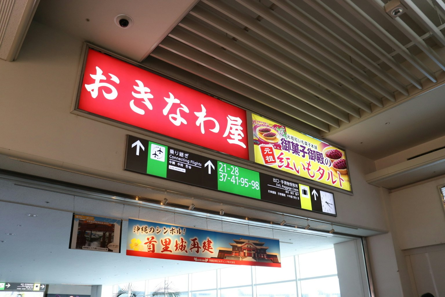 Interno di una struttura commerciale con insegna di un negozio di Okinawa e segnaletica direzionale