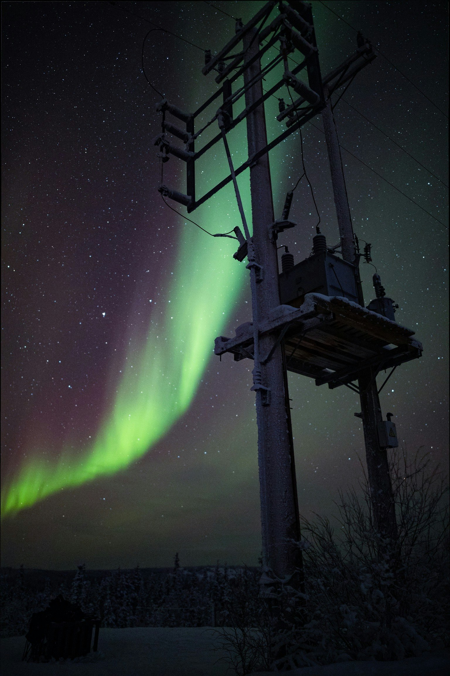 Aurore boréale illuminant le ciel nocturne avec silhouette de lignes électriques