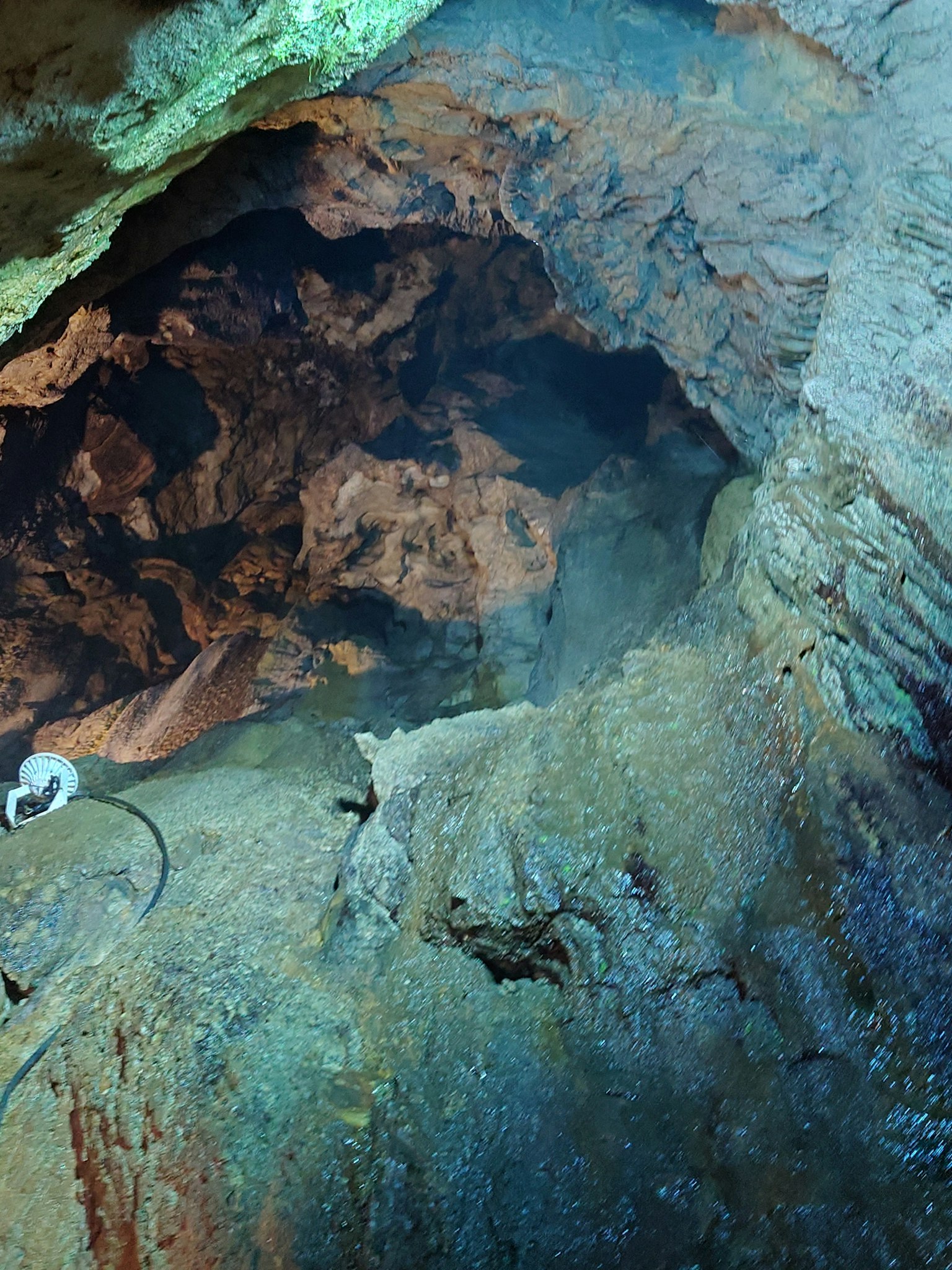 Bild, das das Innere einer Höhle mit strukturierten Felsen und blauer Beleuchtung zeigt