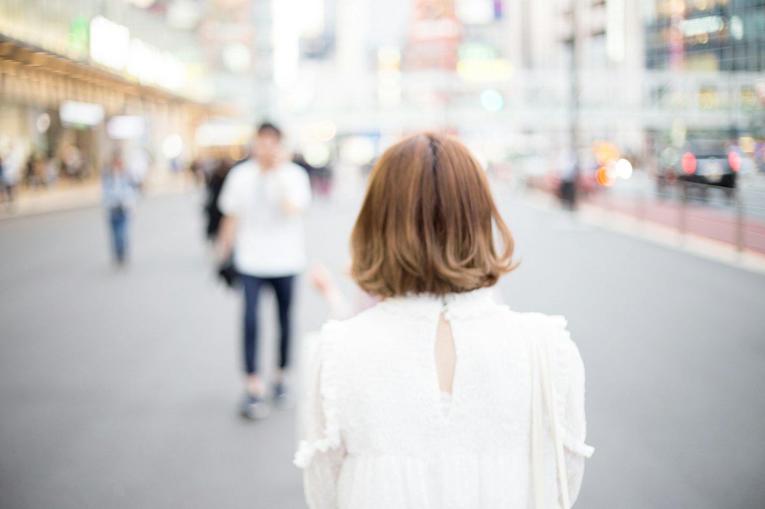 바쁜 도시 환경에서 뒤에서 본 흰색 옷을 입은 여성