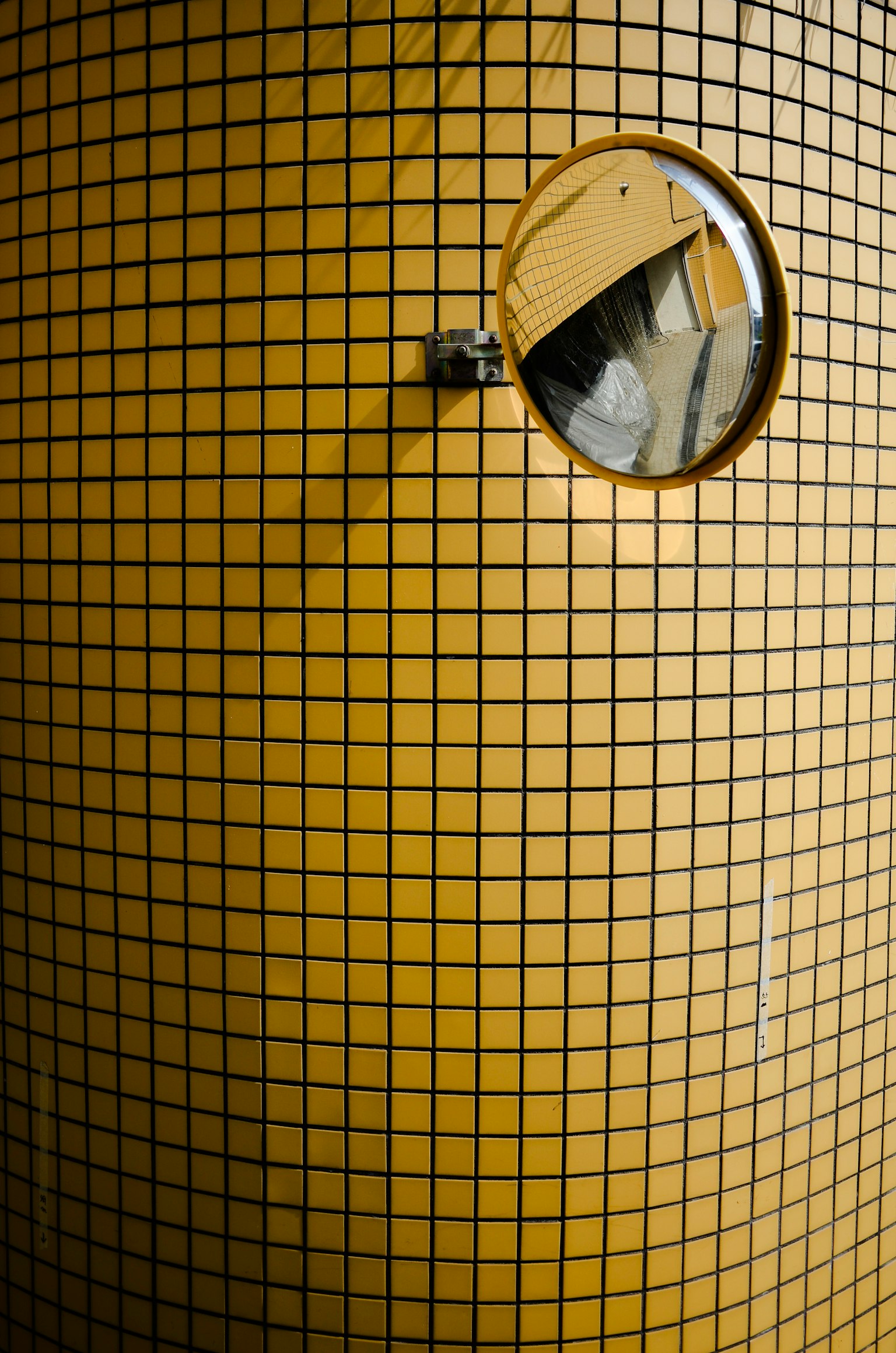 Espejo redondo adjunto a una pared con patrón de cuadrícula amarilla