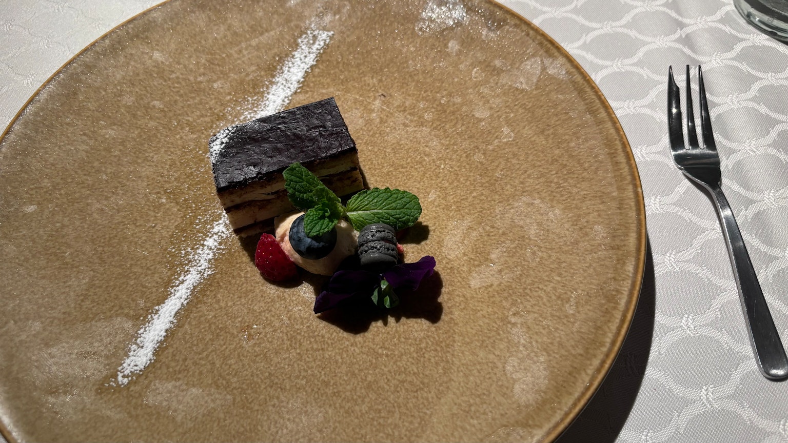 A beautifully arranged dessert on a plate with fruits and mint leaves garnishing