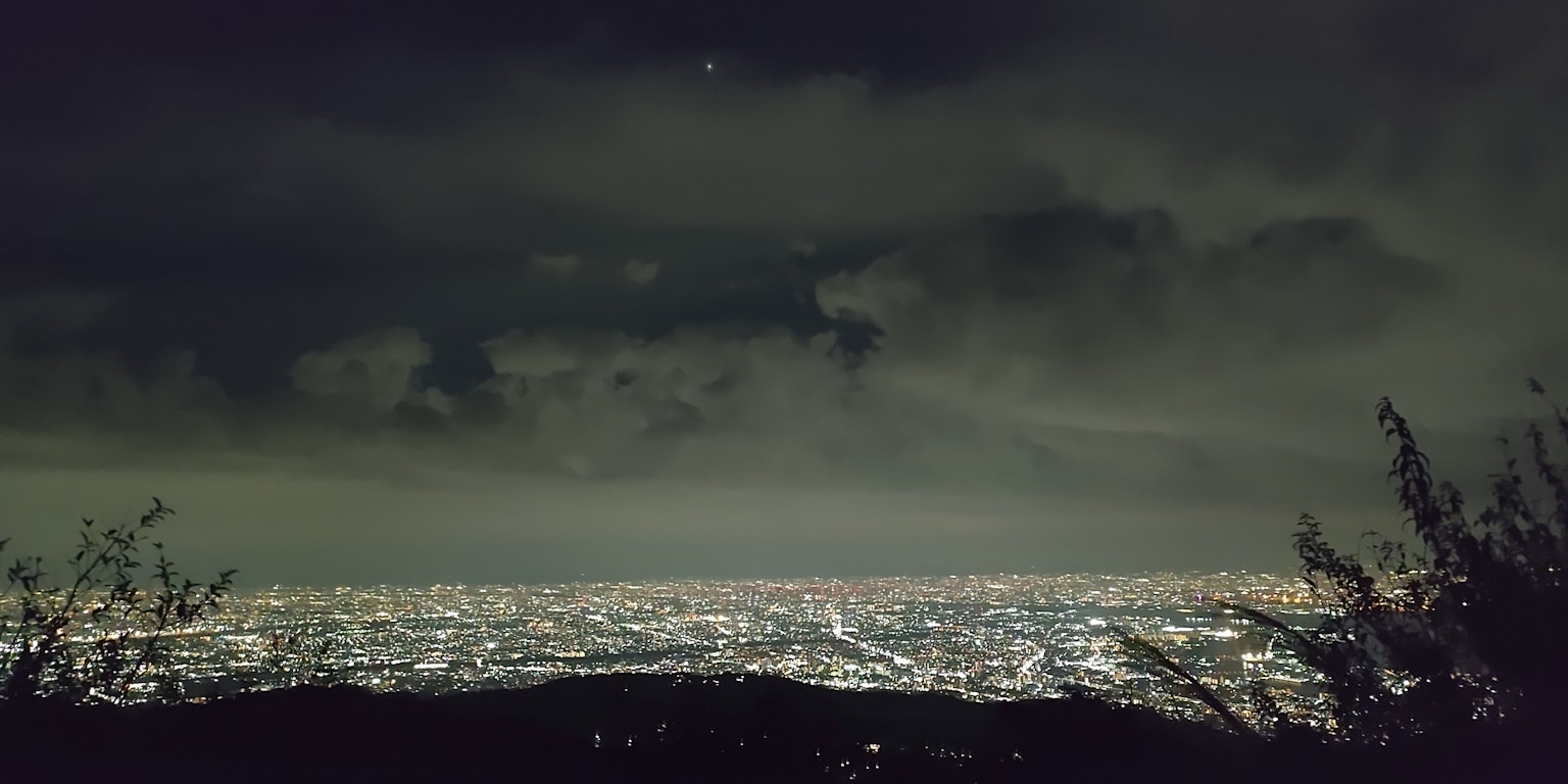 Nächtliche Szene mit Wolken und Stadtlichtern, die den Horizont erleuchten