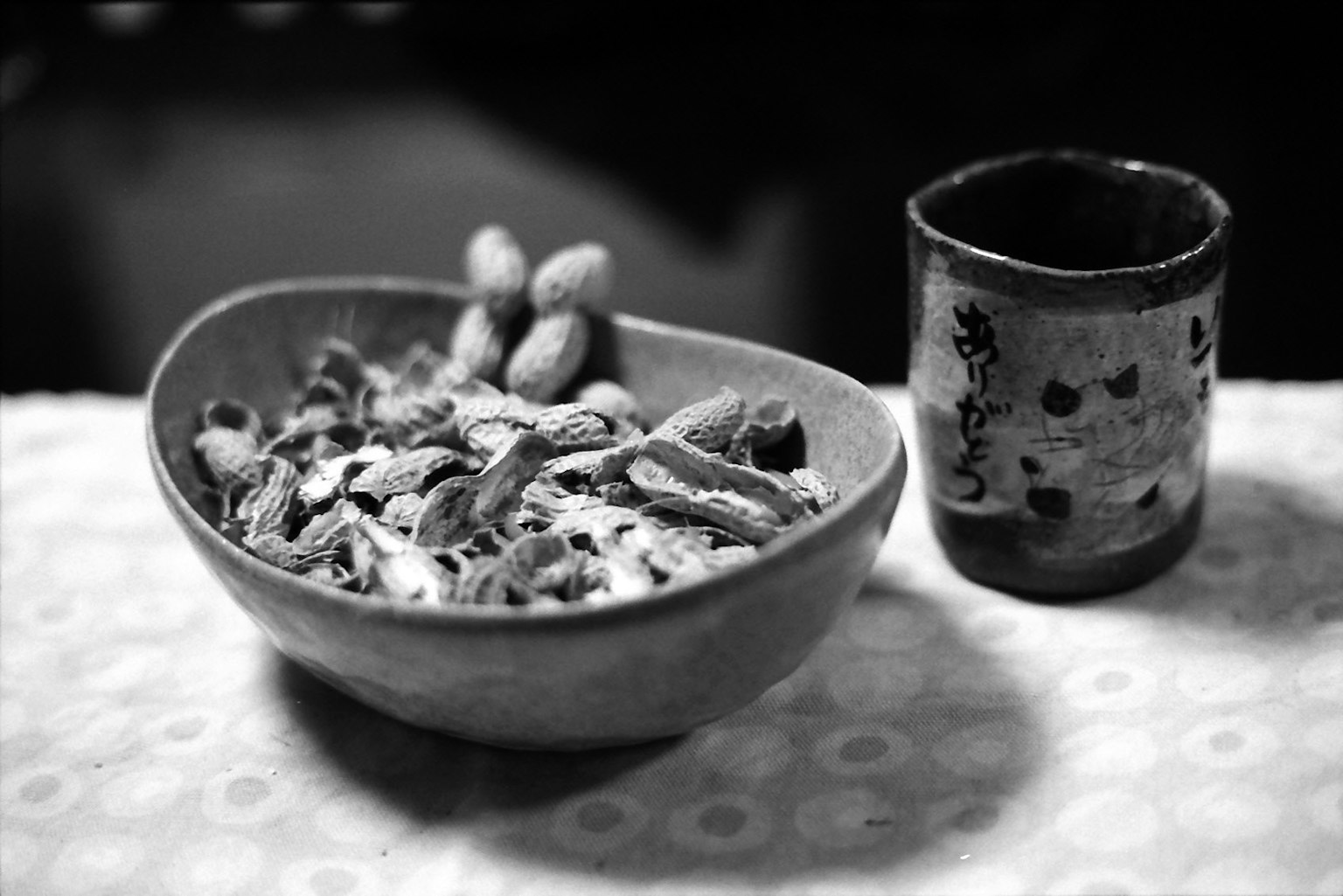 Ciotola di noci in bianco e nero con una tazza accanto