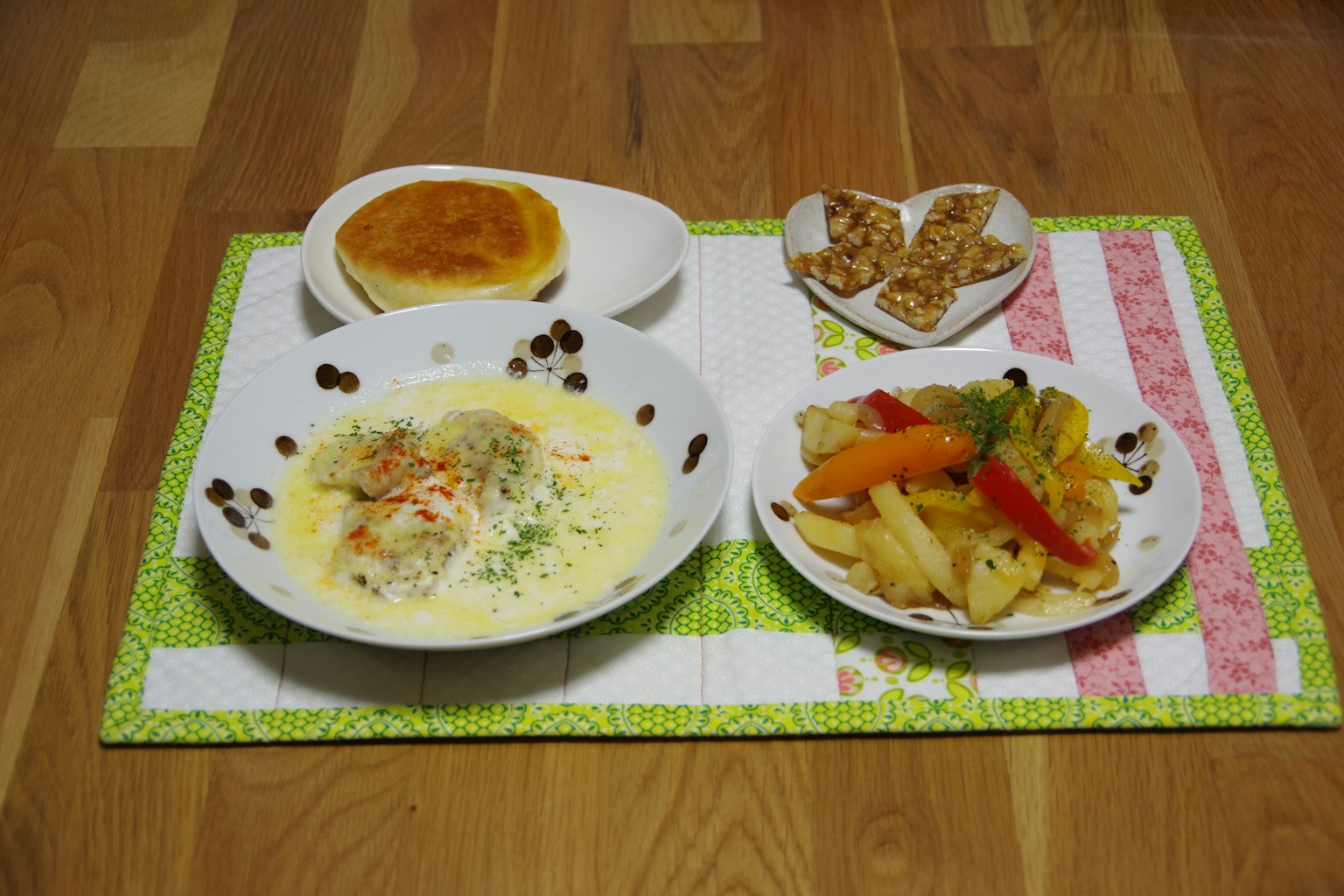 Un plat coloré de légumes et un plat crémeux servi avec du pain et des collations