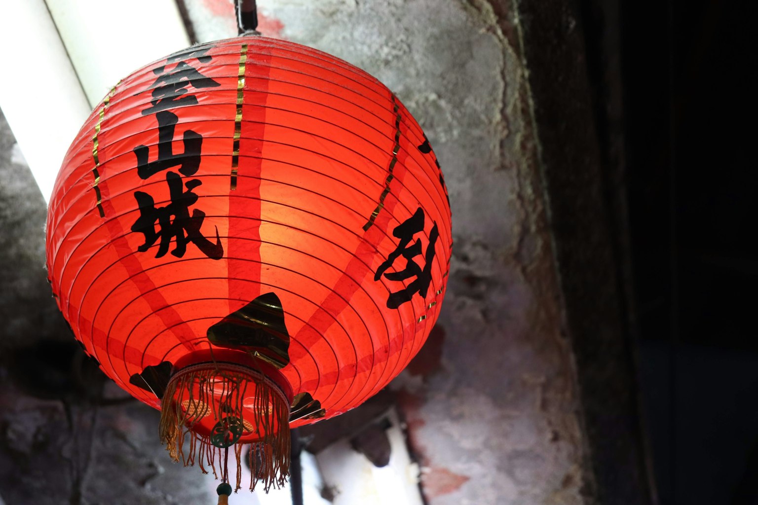 A red lantern hanging near an old wall
