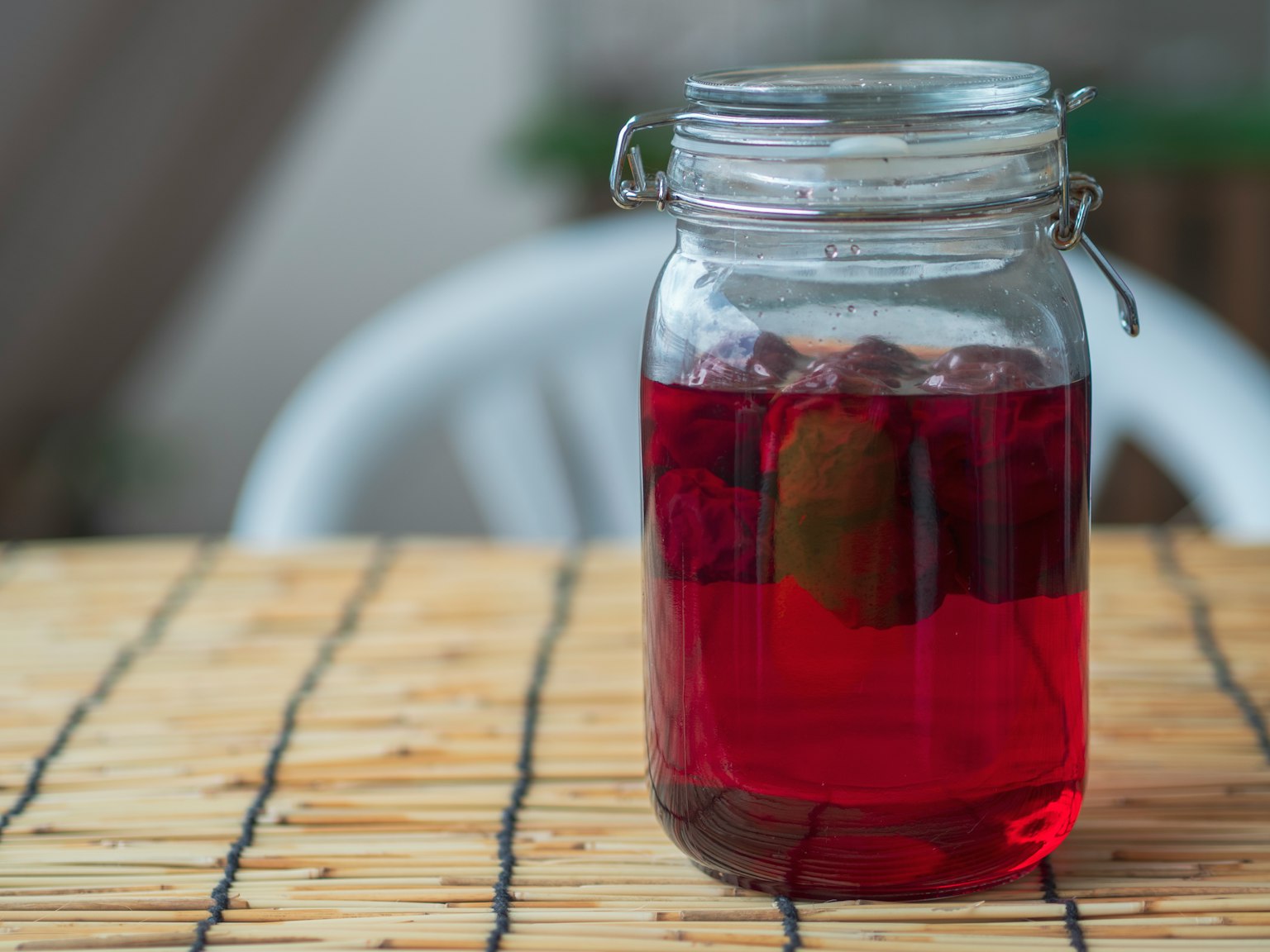 Bocal en verre avec une boisson rouge sur une table en bois