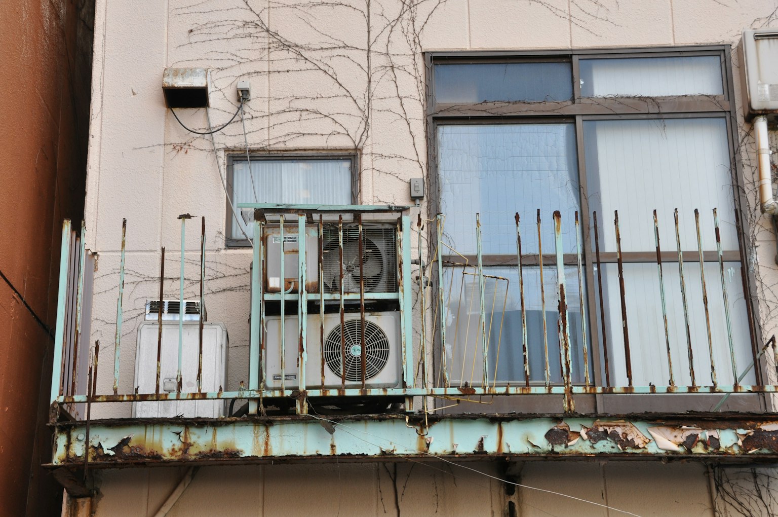 Air conditioning units on a weathered balcony with rusted railings