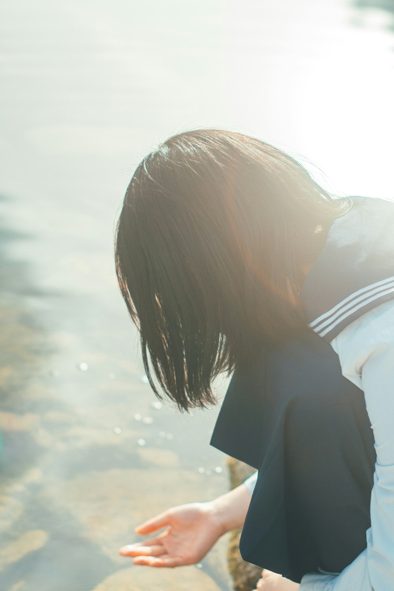 海辺で髪をなびかせる横顔の女性