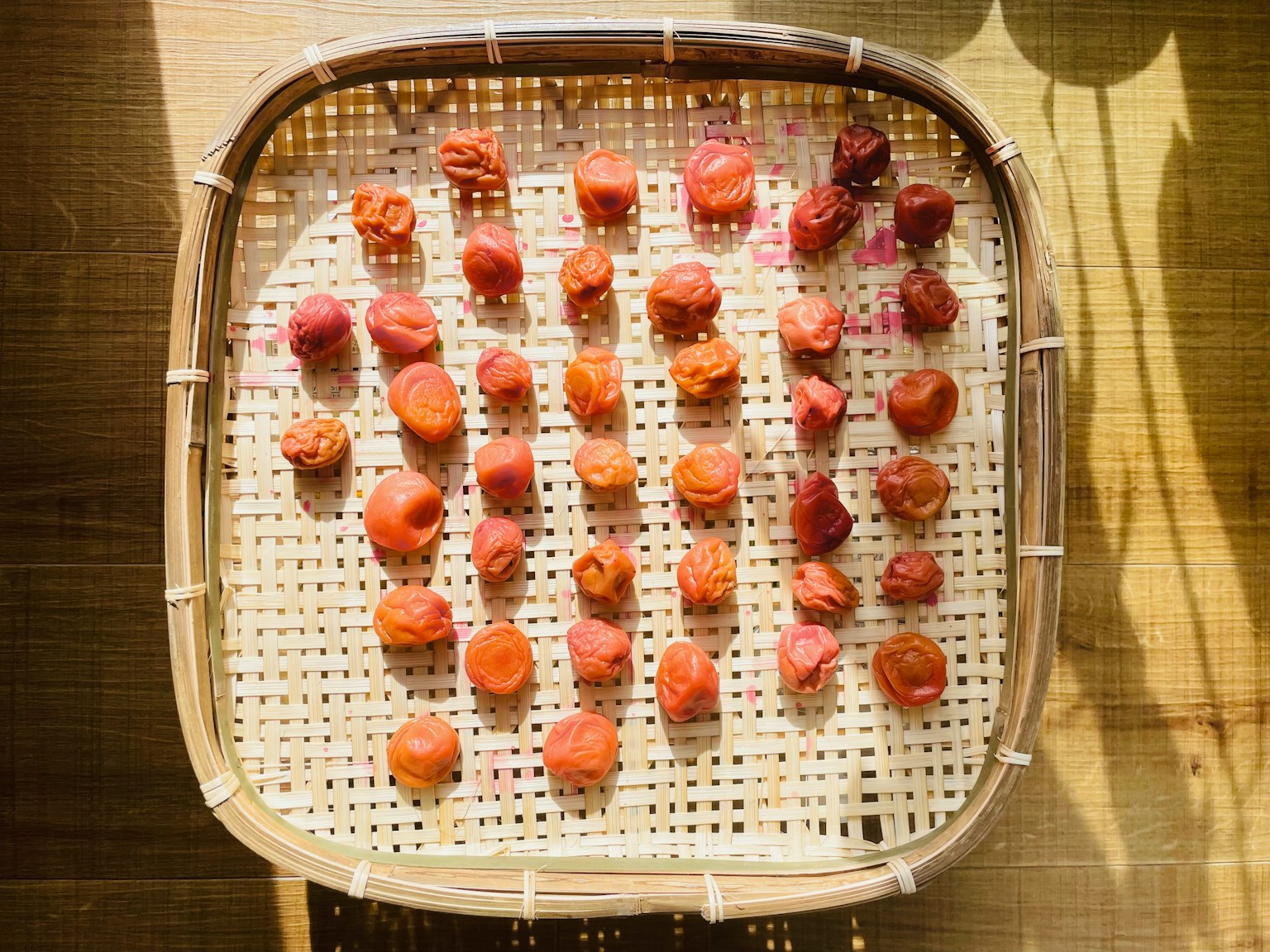 Red fruits resembling umeboshi arranged in a wooden basket