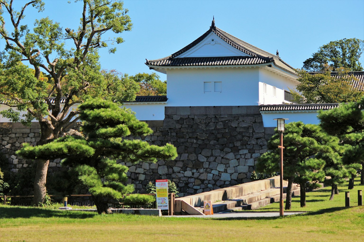 一部分日本城堡，周围有白色墙壁和绿色松树