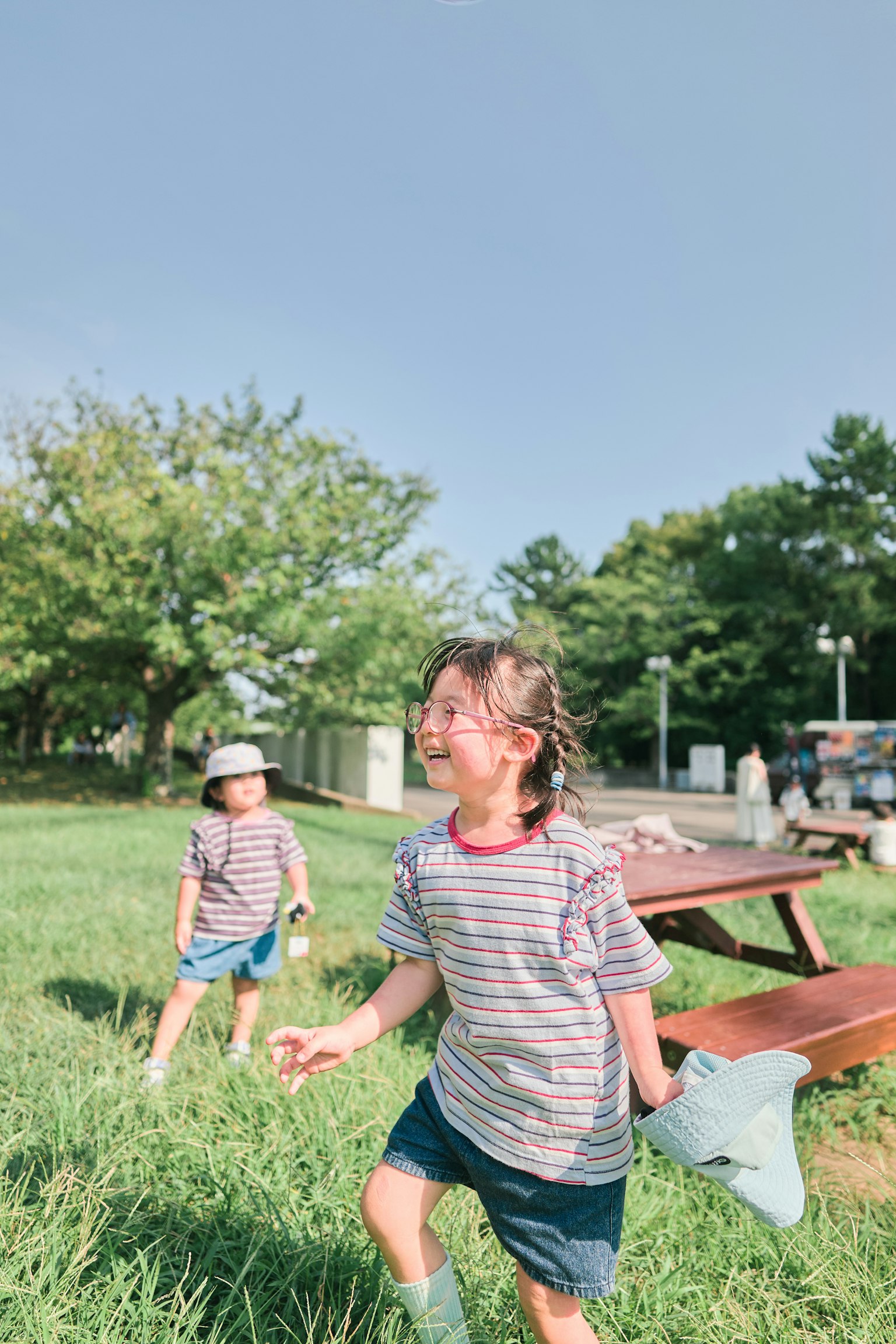 公園で遊ぶ子供たち 笑顔で走る女の子たち 緑の草と青い空