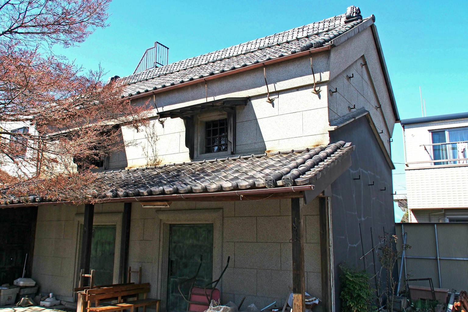 Exterior de una casa japonesa antigua con techo de tejas y paredes blancas rodeadas de árboles