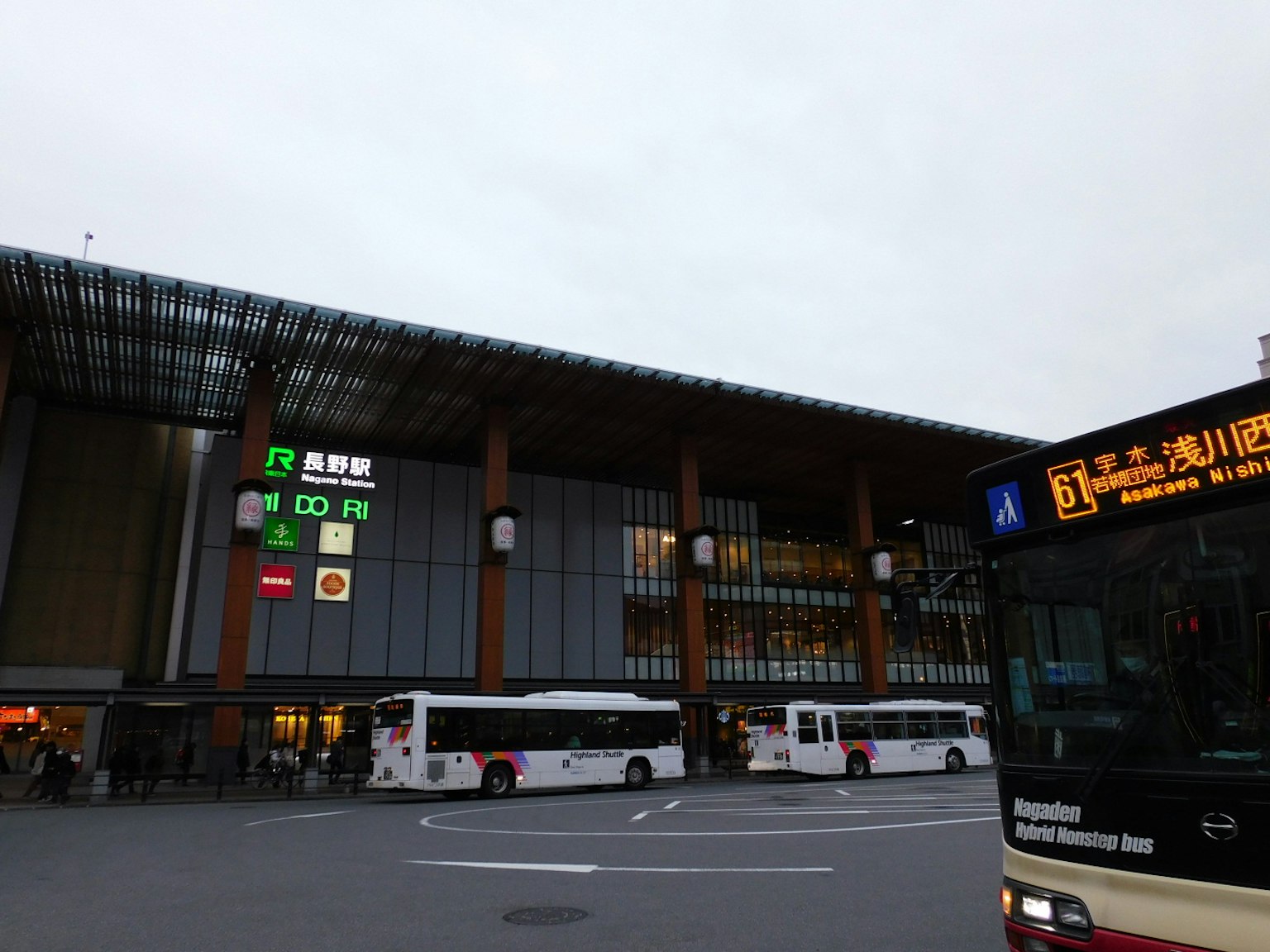 Exterior de una estación de autobuses con autobuses estacionados y cielo nublado