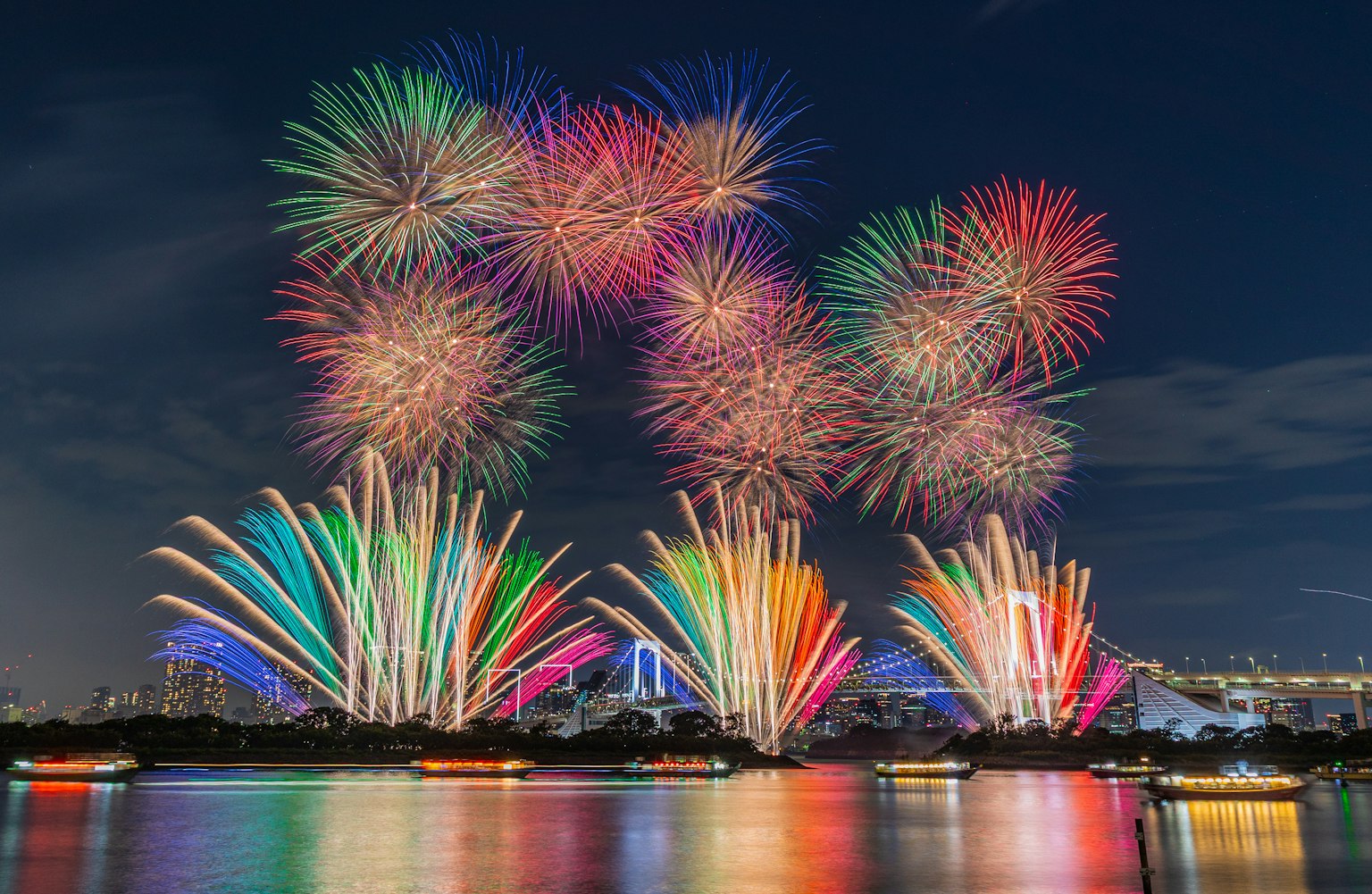 Fuochi d'artificio colorati che esplodono nel cielo notturno riflettendosi sull'acqua