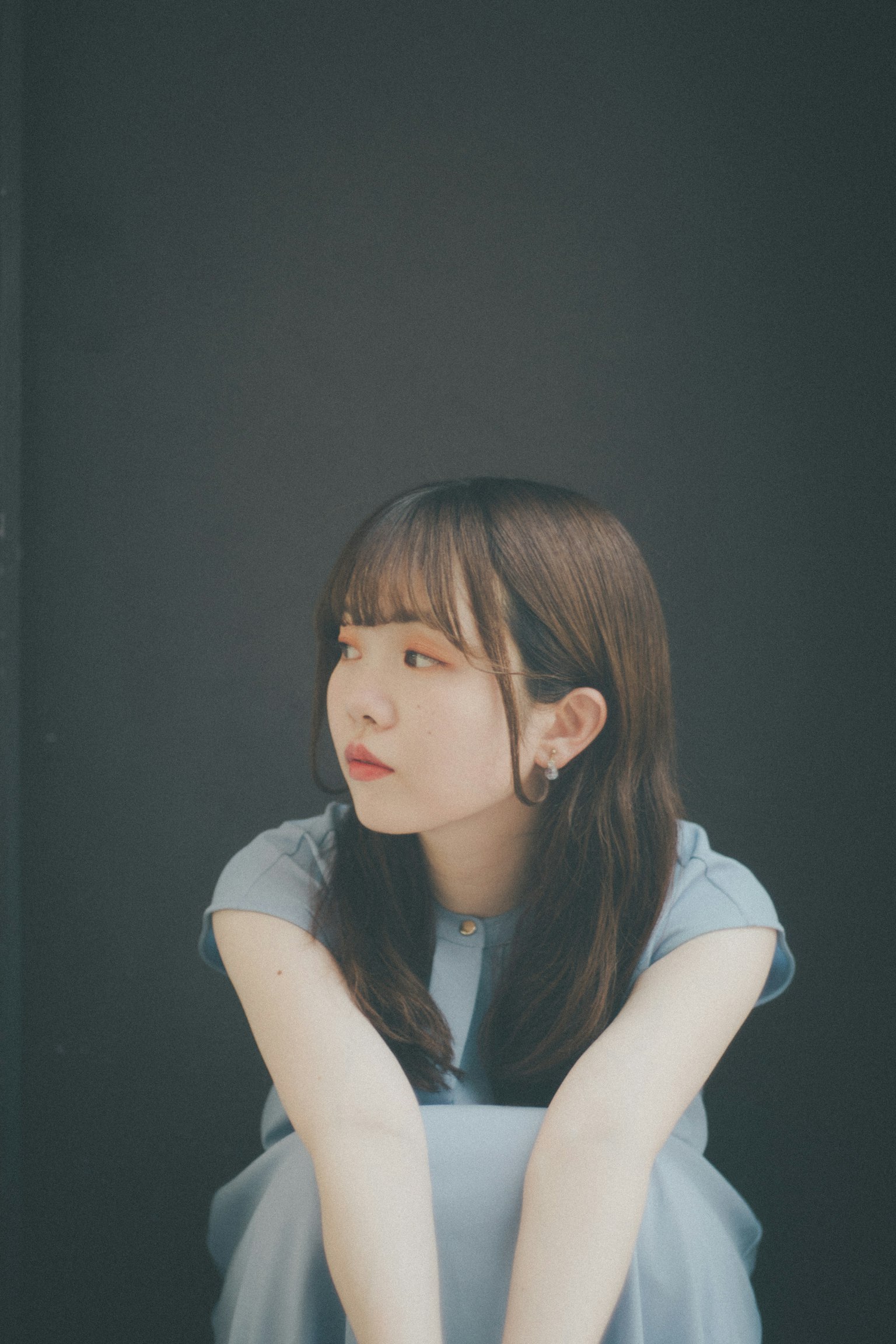A woman sitting quietly in a blue dress