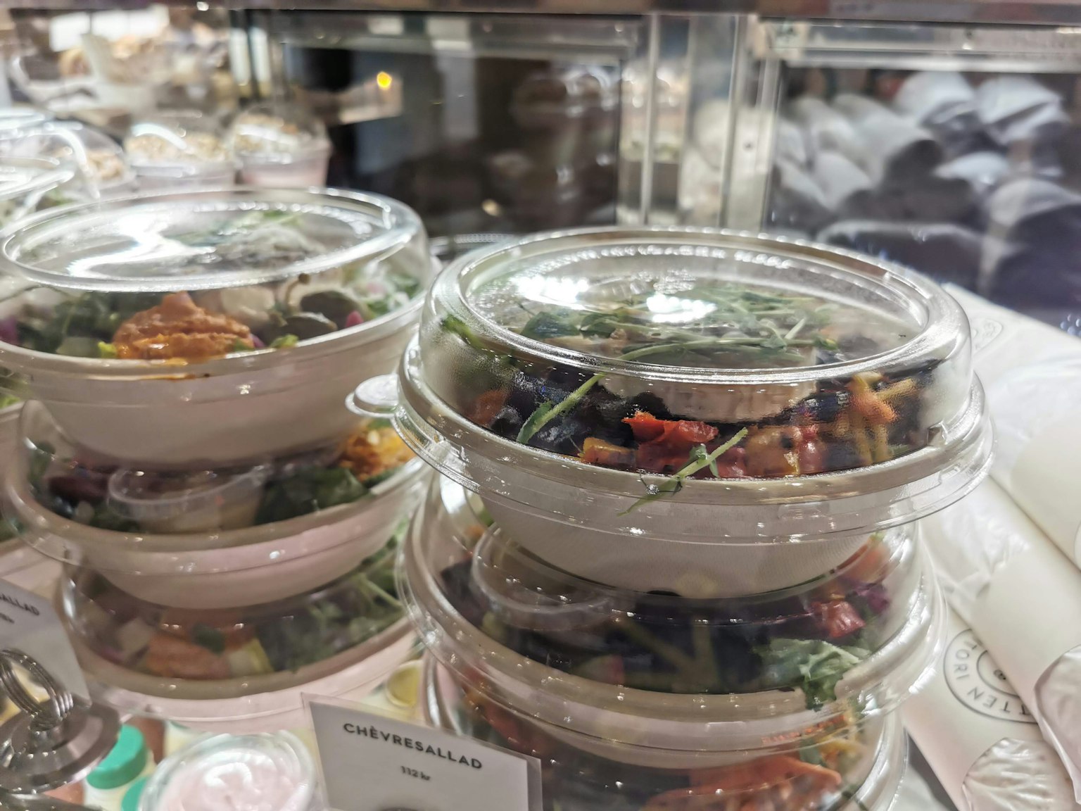 Stacked salad bowls in clear containers with colorful ingredients