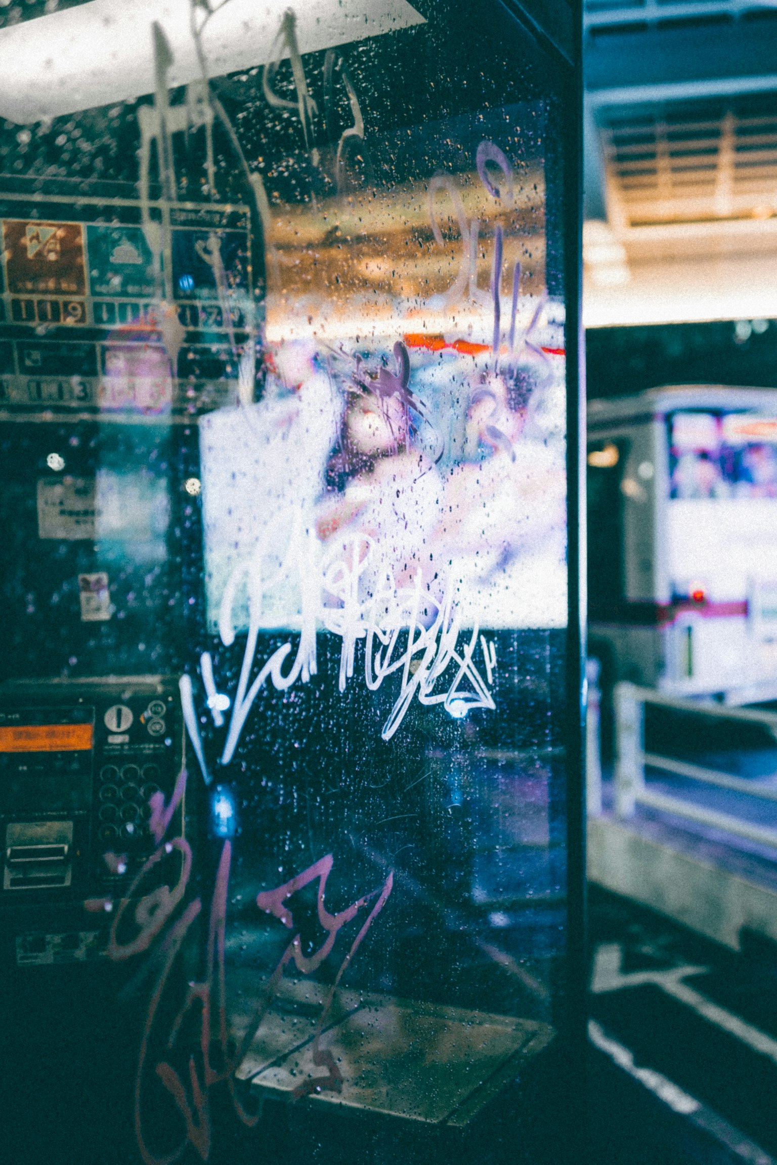 Graffiti an einer transparenten Glaswand mit einem verschwommenen Fernseher im Hintergrund