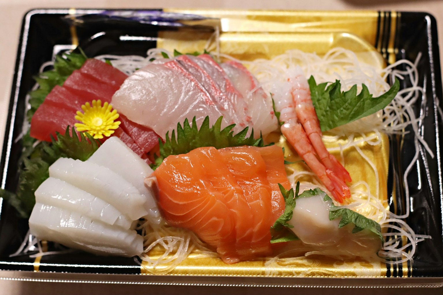 Fresh sashimi platter featuring salmon tuna white fish shrimp garnished with noodles and greens