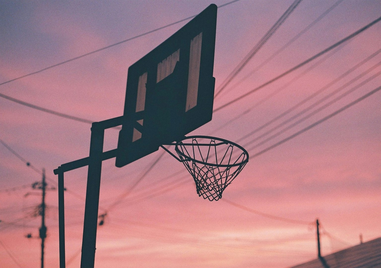 Canestro da basket e rete in silhouette contro un cielo al tramonto