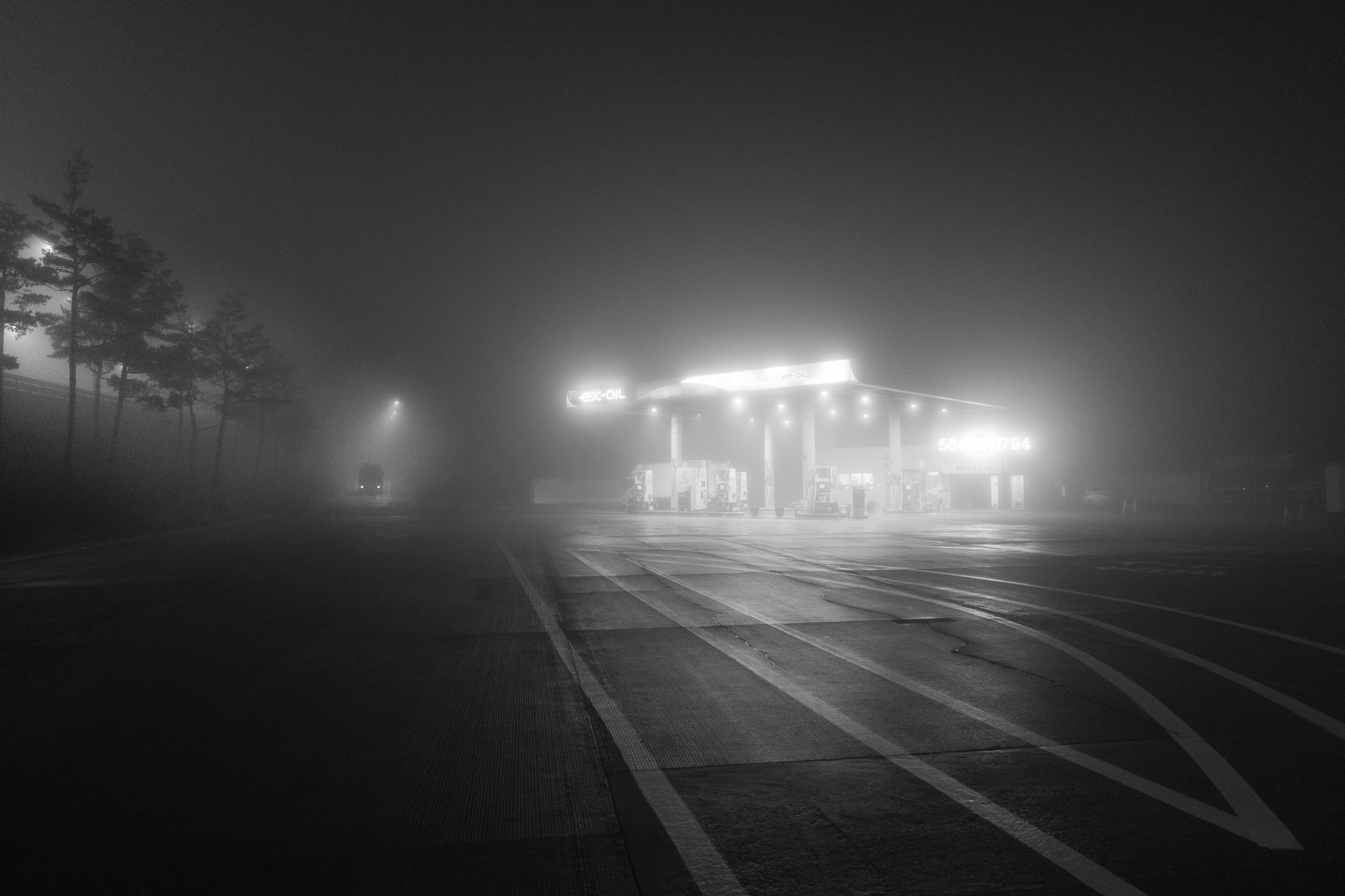 Persimpangan malam berkabut dengan cahaya lampu jalan yang menyebar