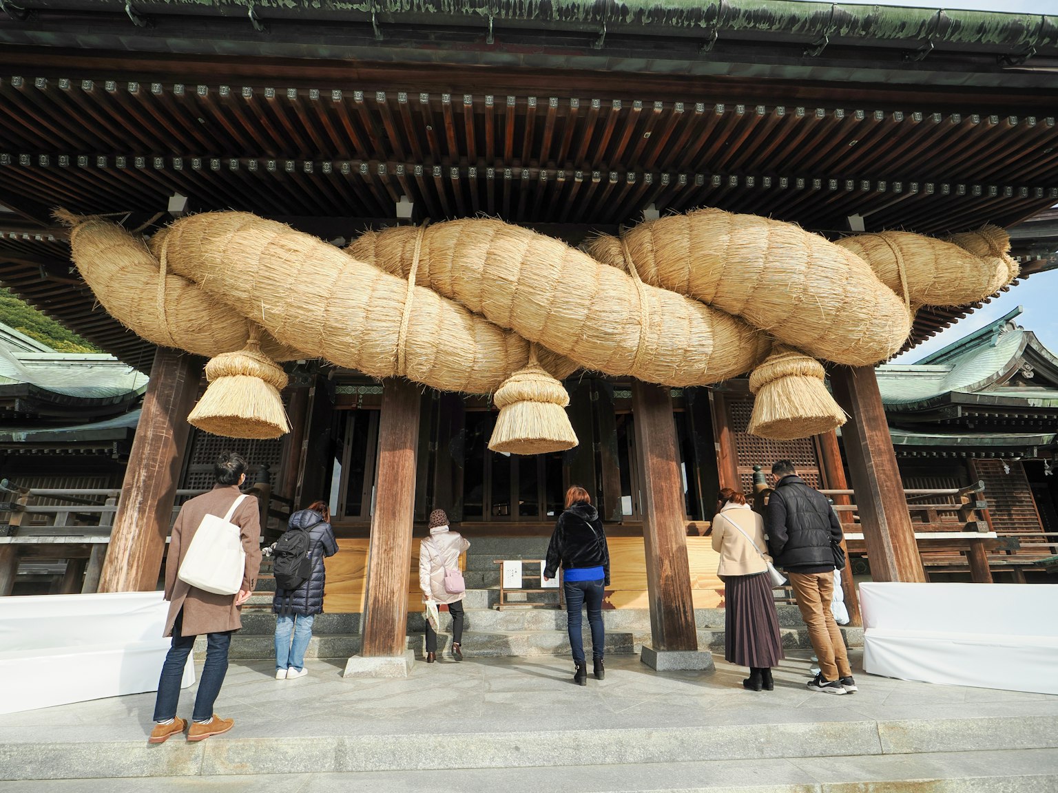 Visiteurs admirant de grandes décorations en paille à l'entrée d'un sanctuaire