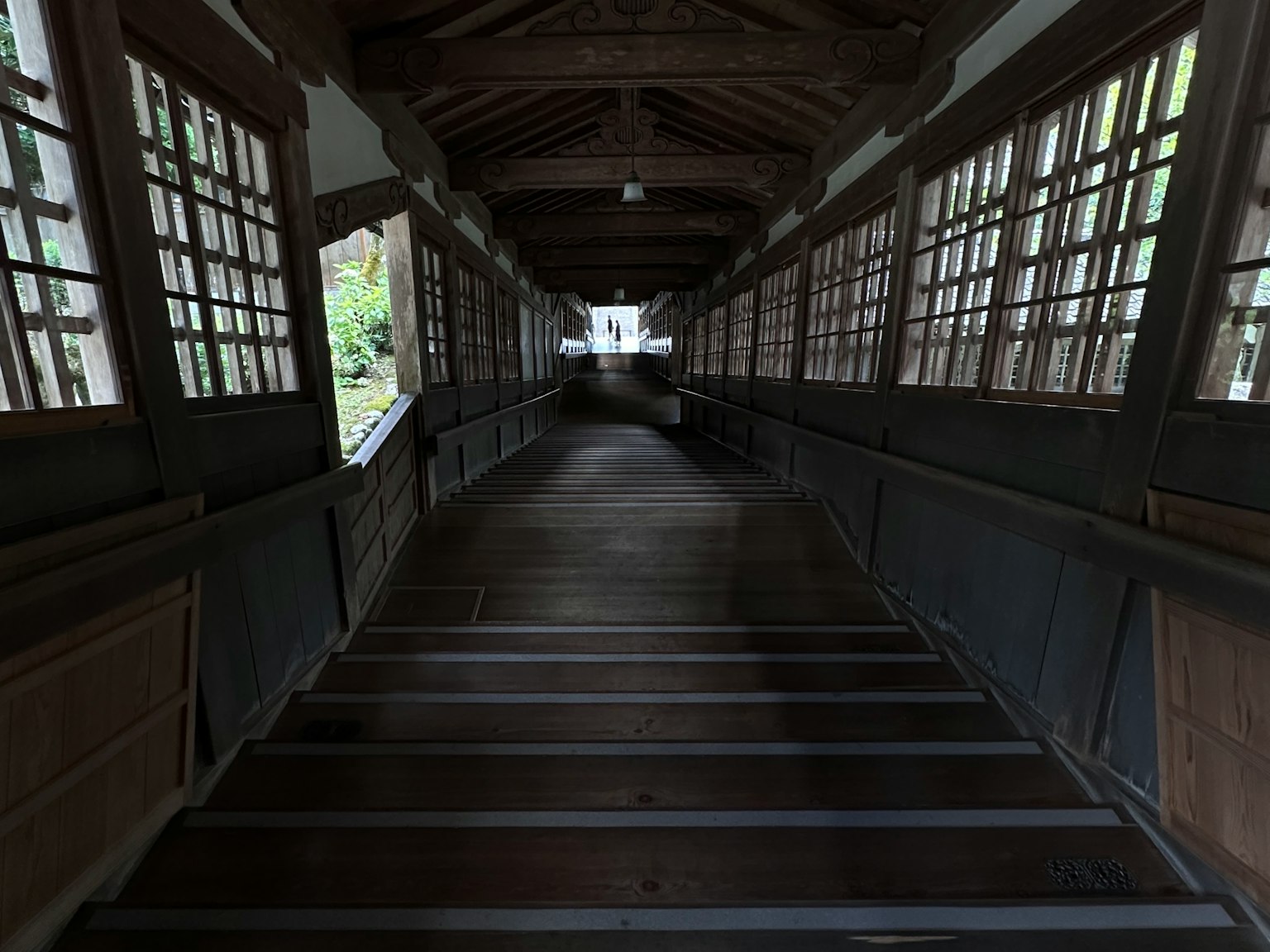 Wooden corridor leading to a bright exit with natural light