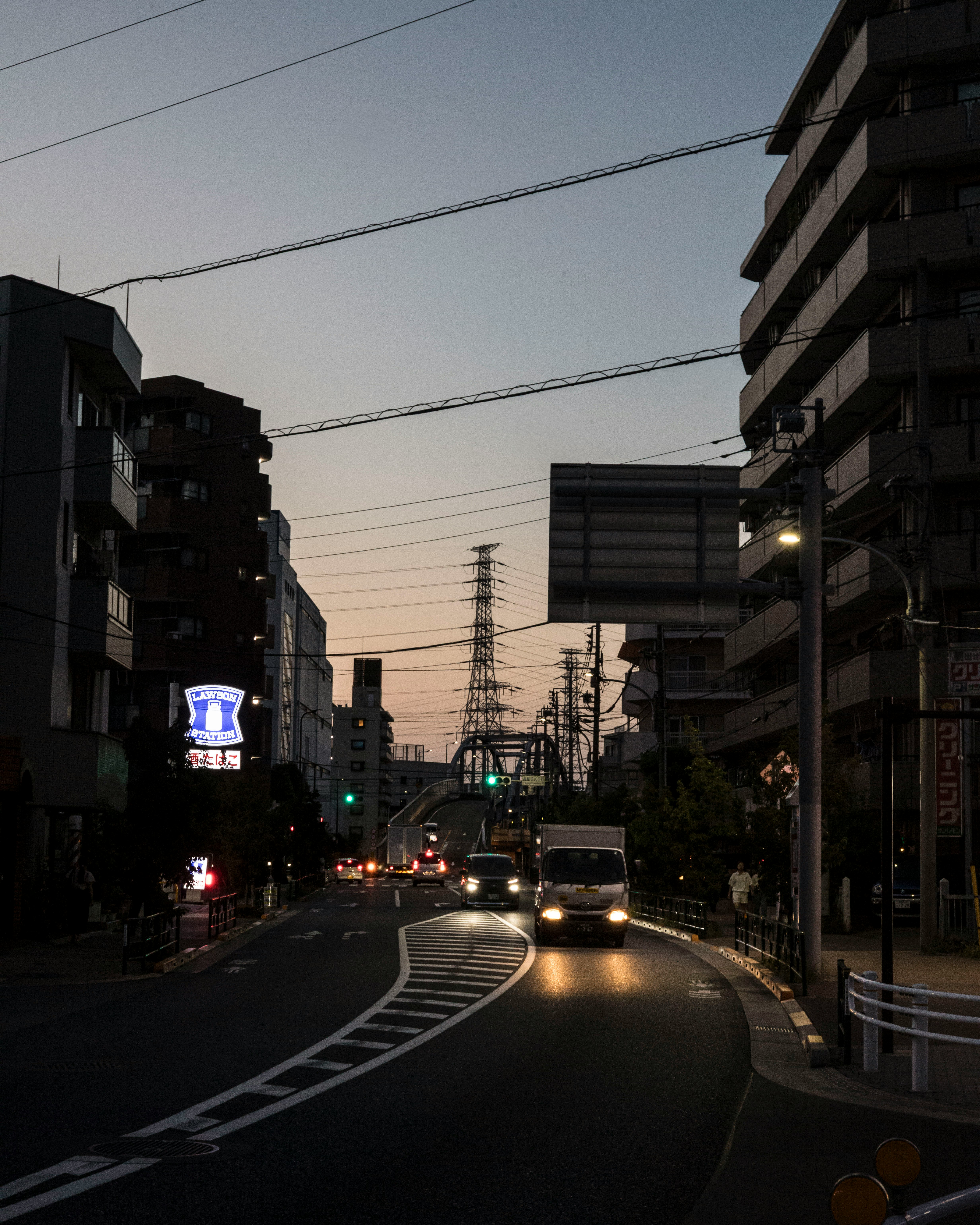 夕暮れの住宅街を走る車と街灯のある通り