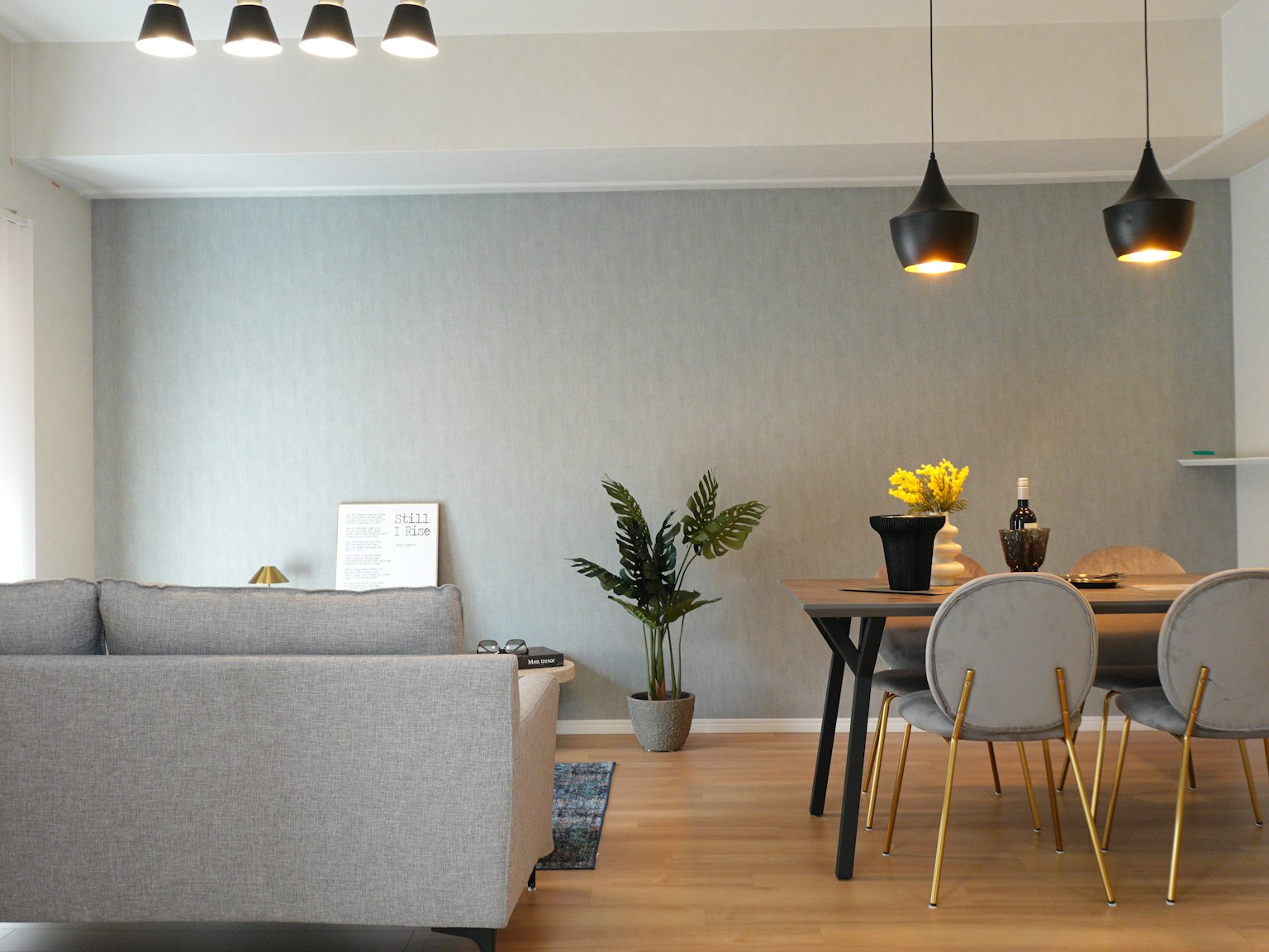 Sala de estar brillante con un sofá gris y una mesa de comedor de madera