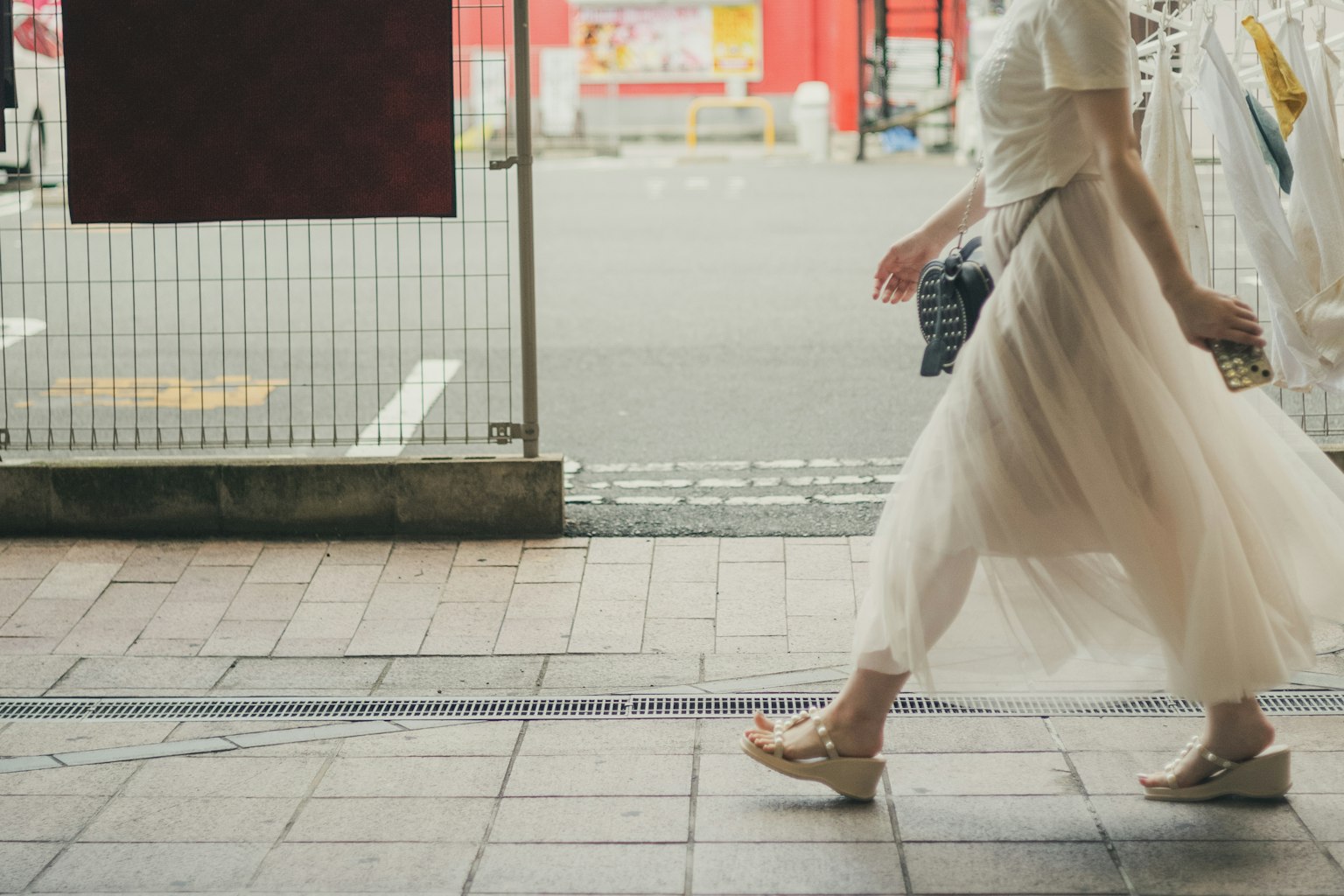 一名女性穿著白色裙子在城市街道上走