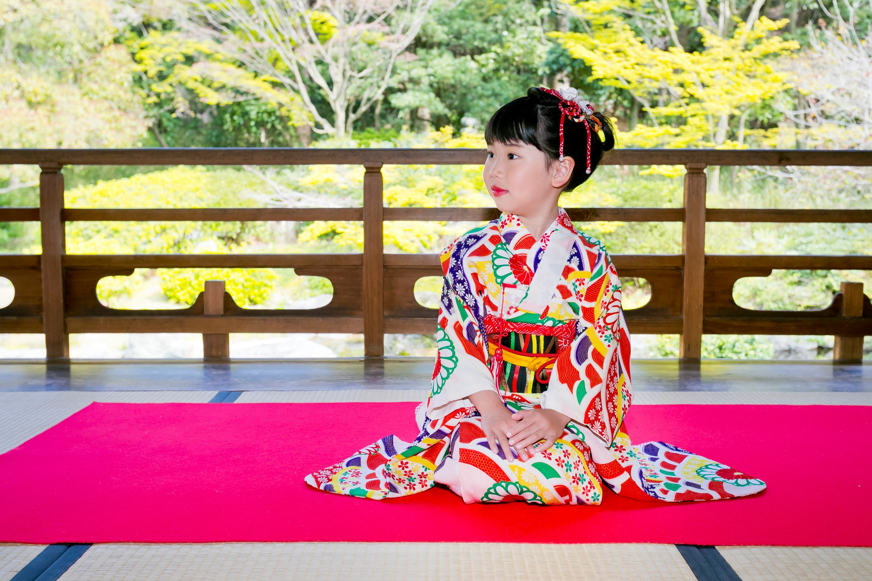 庭のベンチに座る色鮮やかな着物の子ども