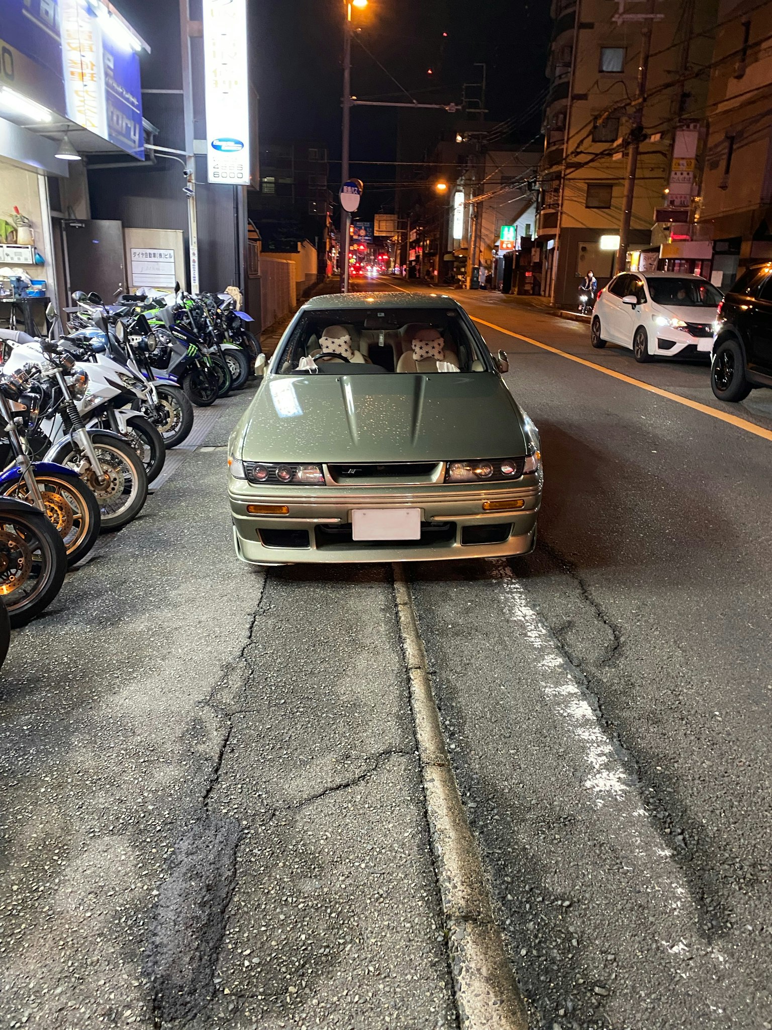 밤에 오토바이와 함께 도로에 주차된 녹색 자동차