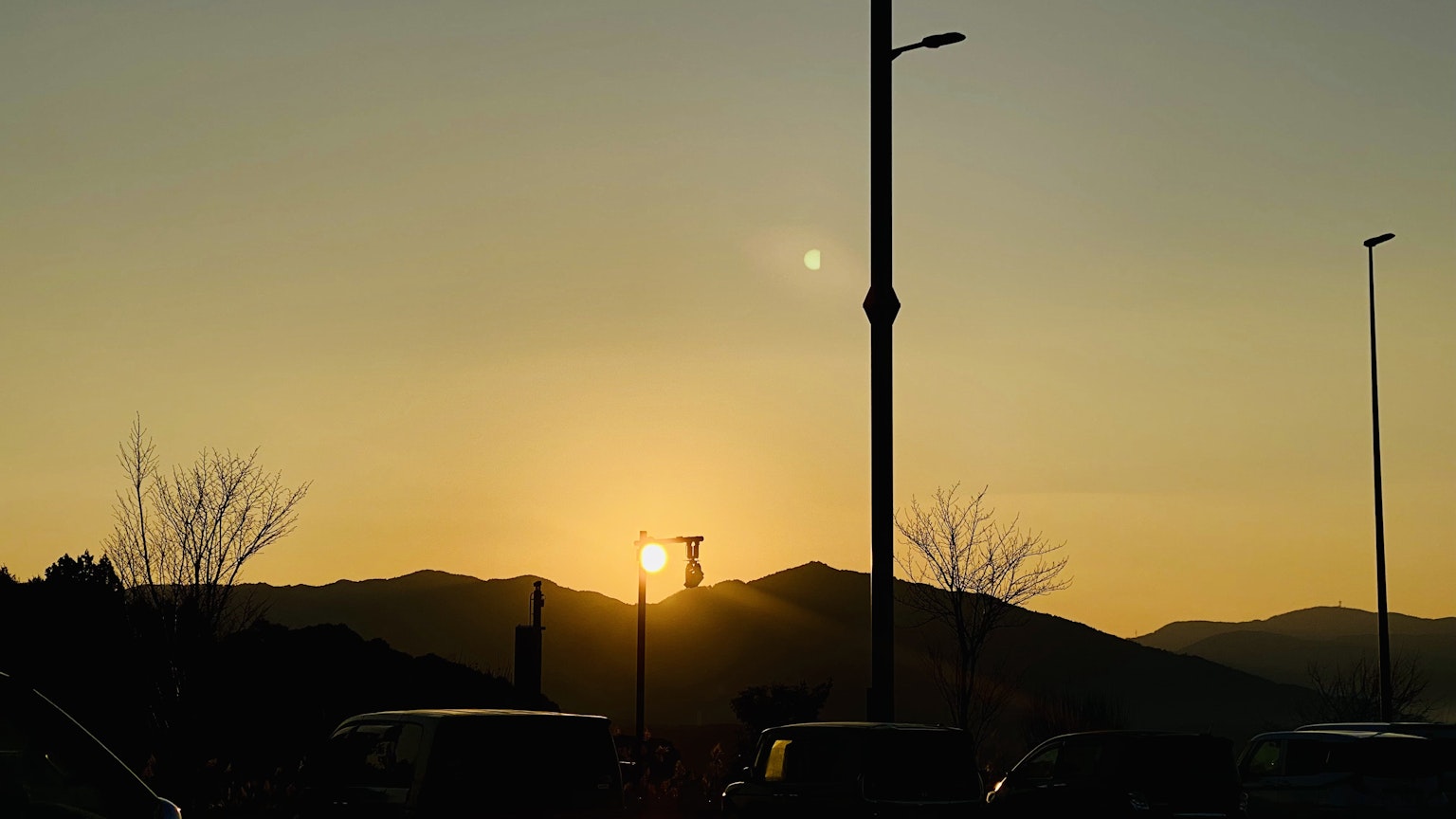 Sonnenuntergang hinter Bergen mit silhouettierter Straßenlaterne