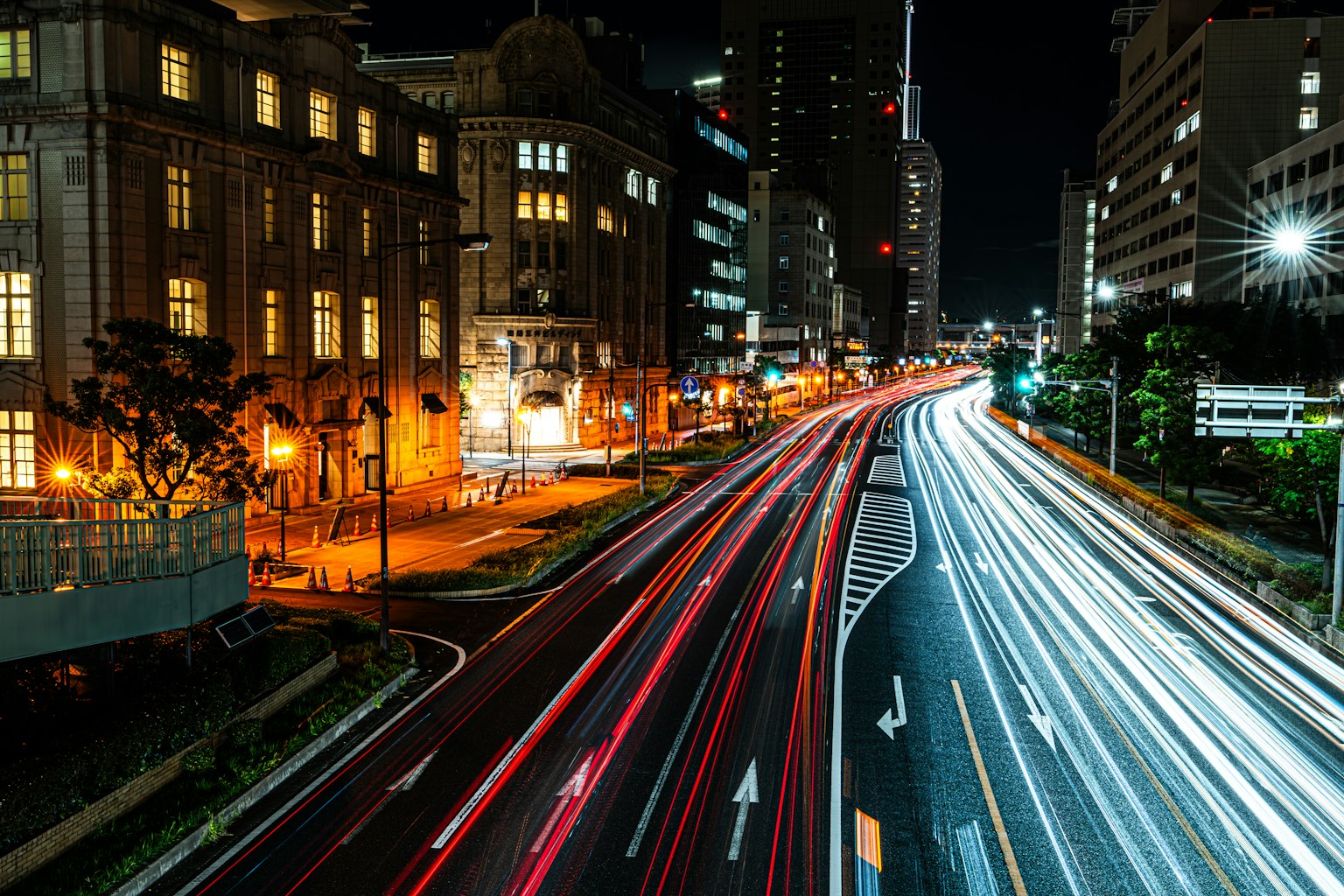 Nachtstadtansicht mit fließenden Autolichtern hellen Straßenlaternen und Gebäuden entlang der Straße